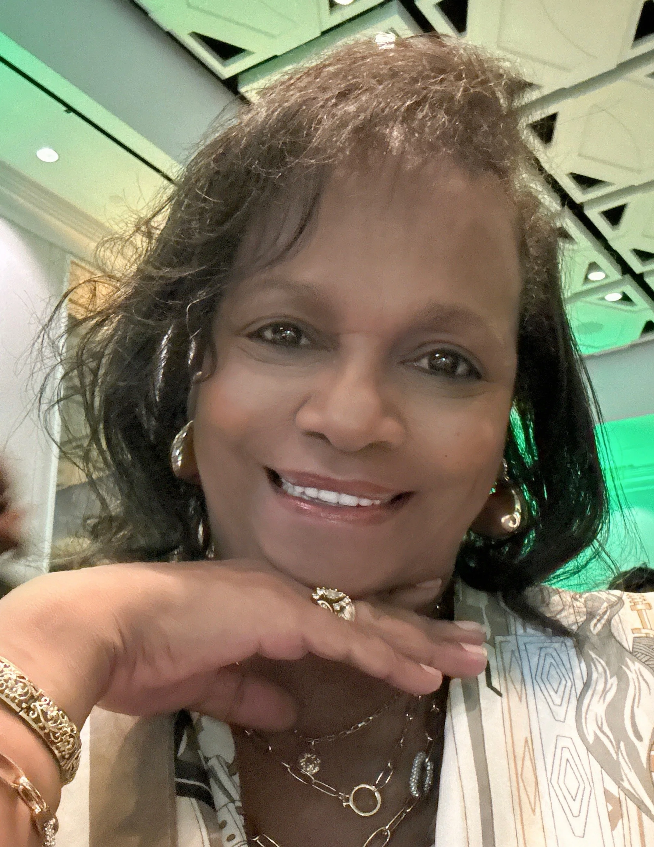 Man with curly hair and glasses wearing a dark green sweater.