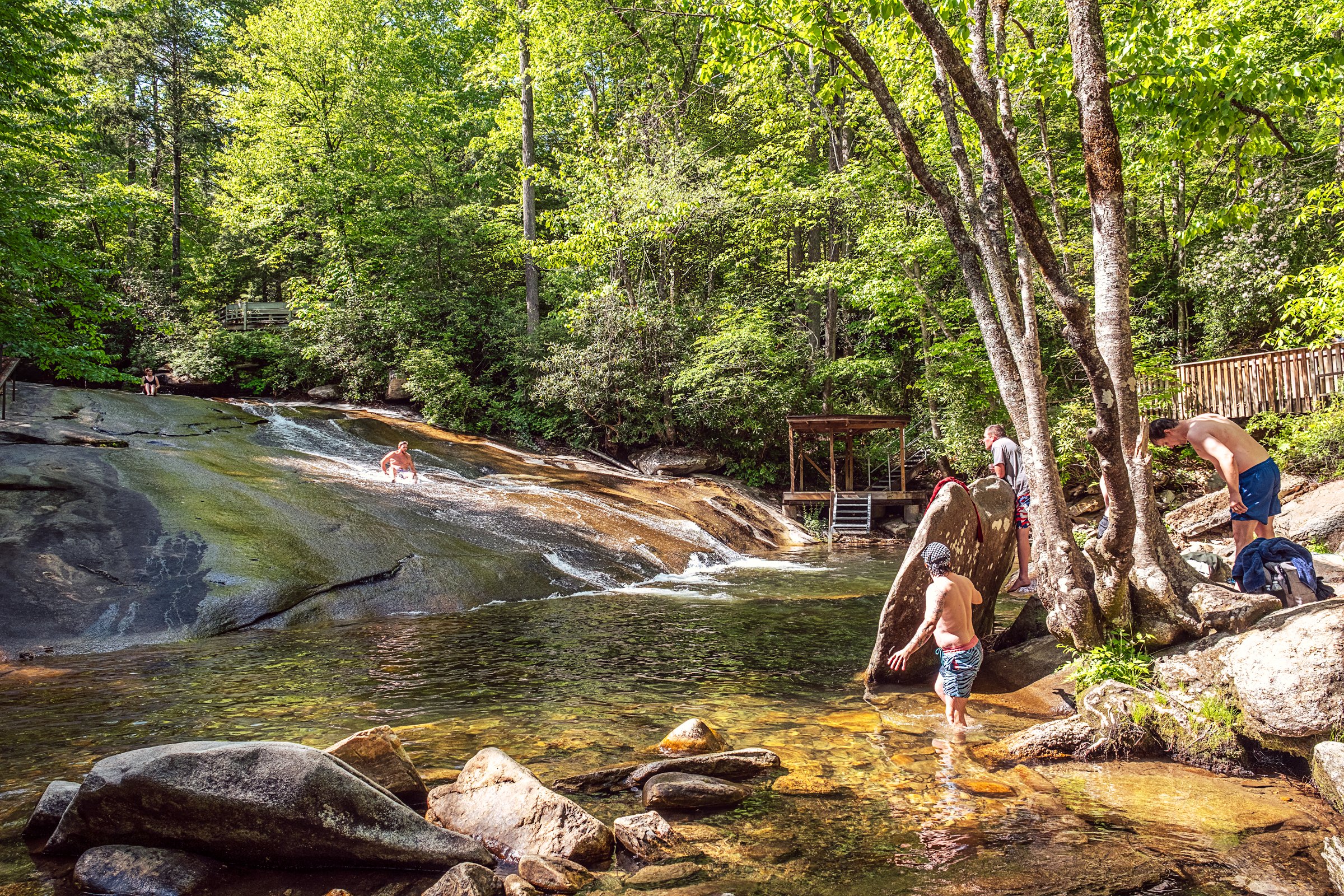 Visitors sliding down Sliding Rock, a natural granite waterslide in Pisgah National Forest near Asheville, North Carolina. Photographed by Lange Photo Studio. 