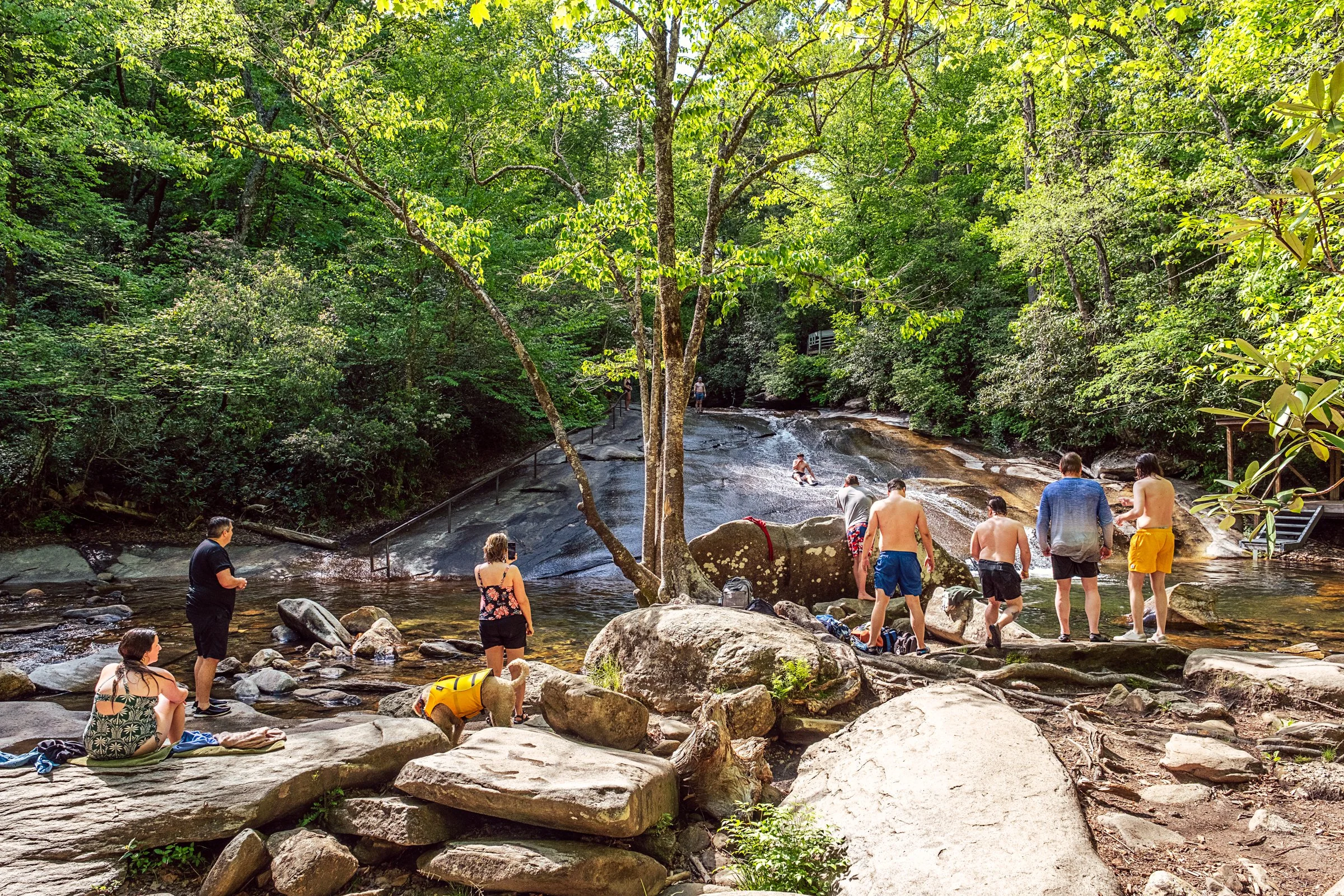 Visitors sliding down Sliding Rock, a natural granite waterslide in Pisgah National Forest near Asheville, North Carolina. Photographed by Lange Photo Studio. 