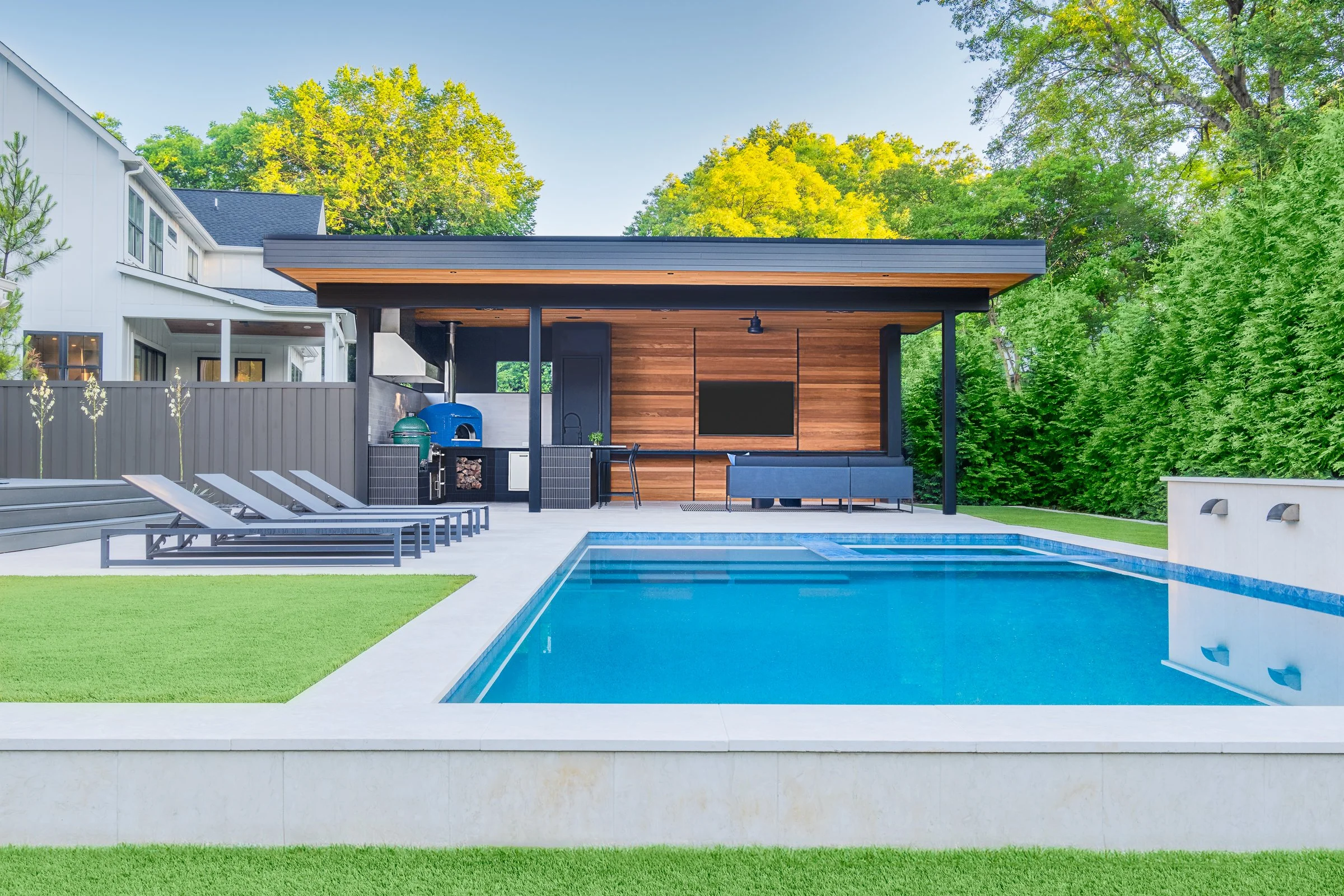 Modern pool pavilion architecture featuring clean lines, natural materials, and seamless indoor-outdoor living spaces in Charlotte, North Carolina. This contemporary structure showcases floor-to-ceiling glass walls, exposed wooden beams, and a minima
