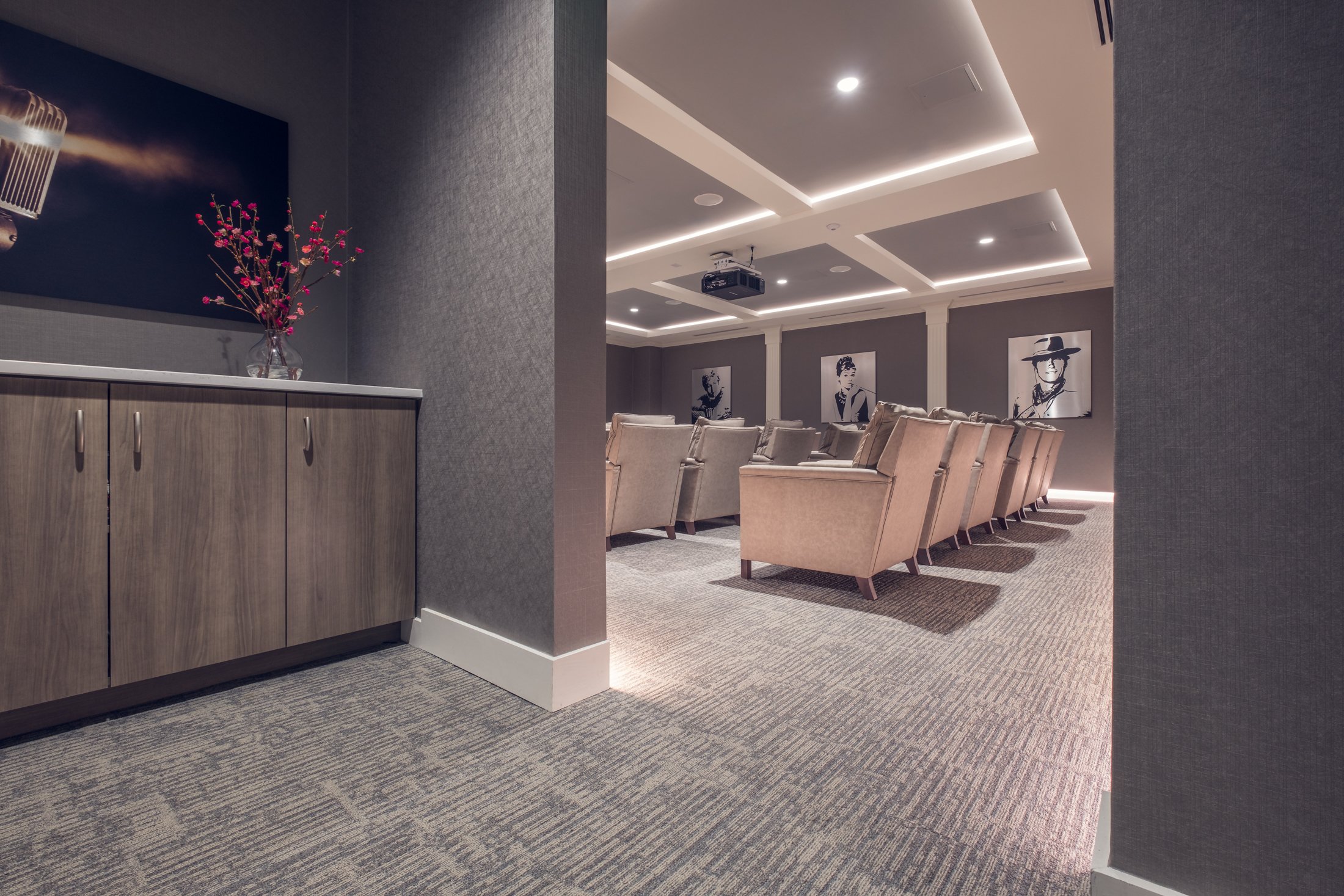 Spacious modern movie theatre of Village on Morehead featuring contemporary furniture, large movie screen, and architectural details