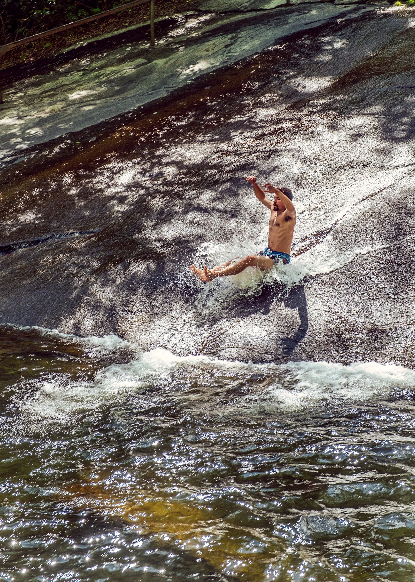 Visitors sliding down Sliding Rock, a natural granite waterslide in Pisgah National Forest near Asheville, North Carolina. Photographed by Lange Photo Studio. 