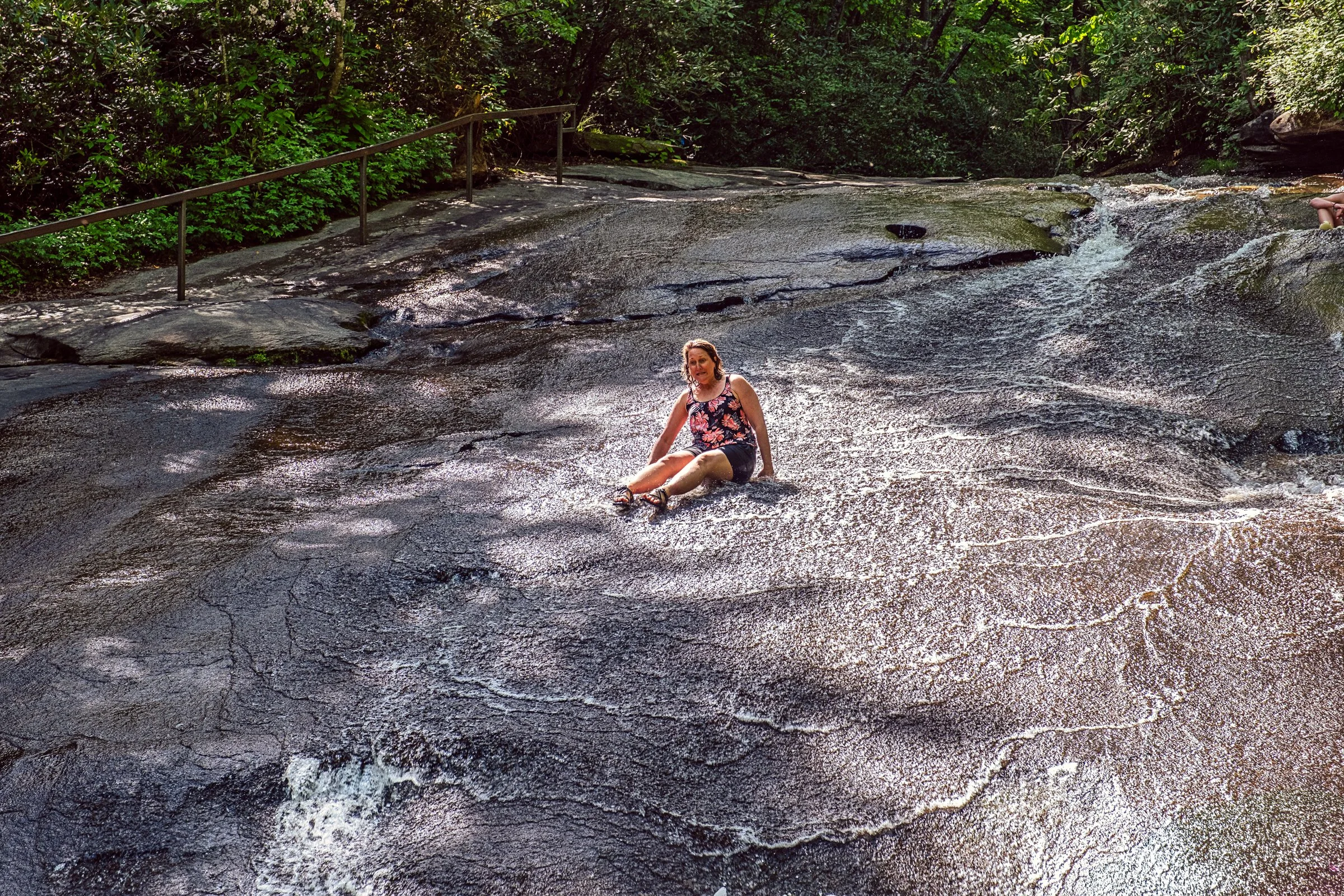 Visitors sliding down Sliding Rock, a natural granite waterslide in Pisgah National Forest near Asheville, North Carolina. Photographed by Lange Photo Studio. 
