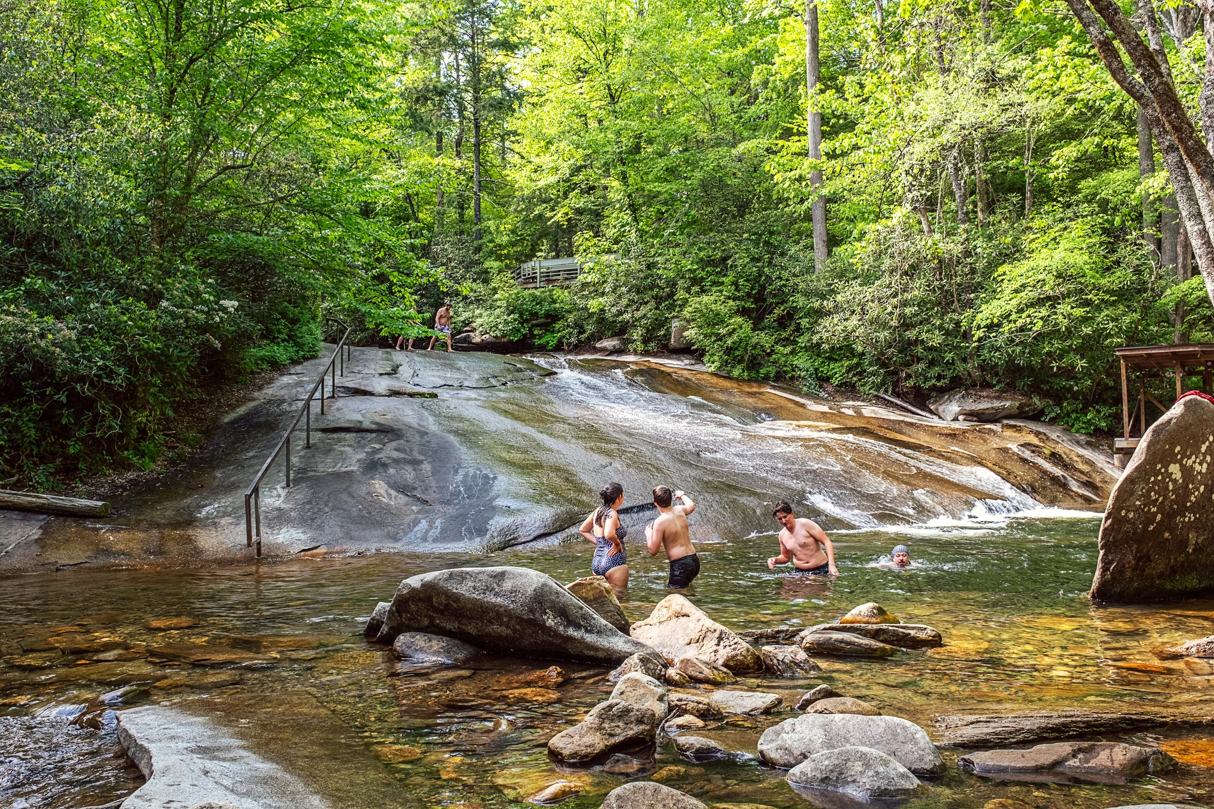 Visitors sliding down Sliding Rock, a natural granite waterslide in Pisgah National Forest near Asheville, North Carolina. Photographed by Lange Photo Studio. 