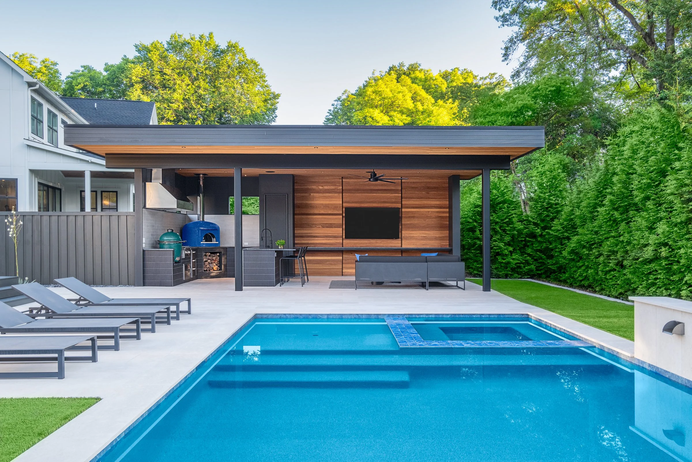 Modern pool pavilion architecture featuring clean lines, natural materials, and seamless indoor-outdoor living spaces in Charlotte, North Carolina. This contemporary structure showcases floor-to-ceiling glass walls, exposed wooden beams, and a minima