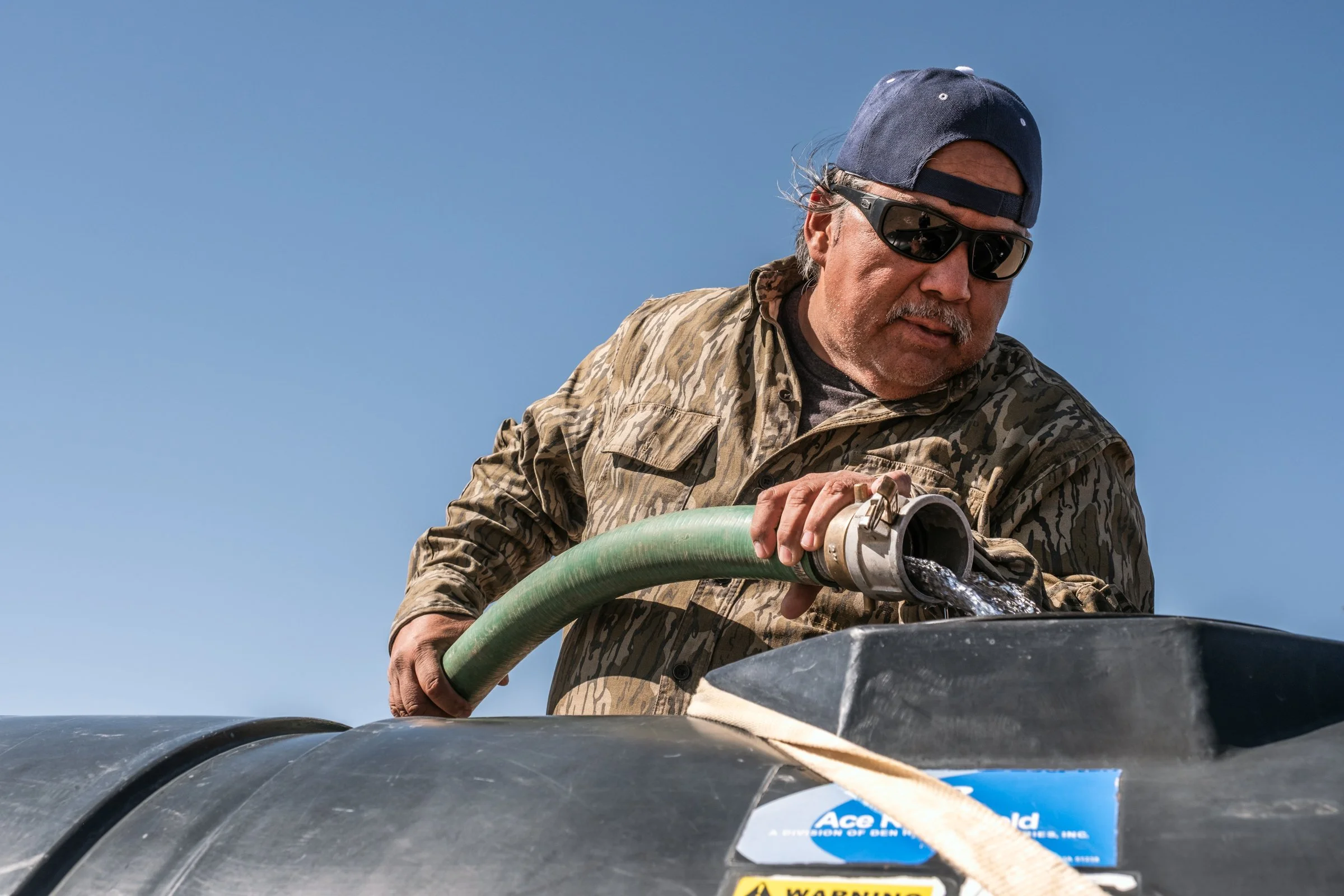 Hauling Life | Navajo Nation — Unified Metadata Paragraphs

Wayne Wilson and Joann Whiting collect water in Gallup, New Mexico at a community water source. The containers are filled, prepared, and loaded into their vehicle for transport across the Na