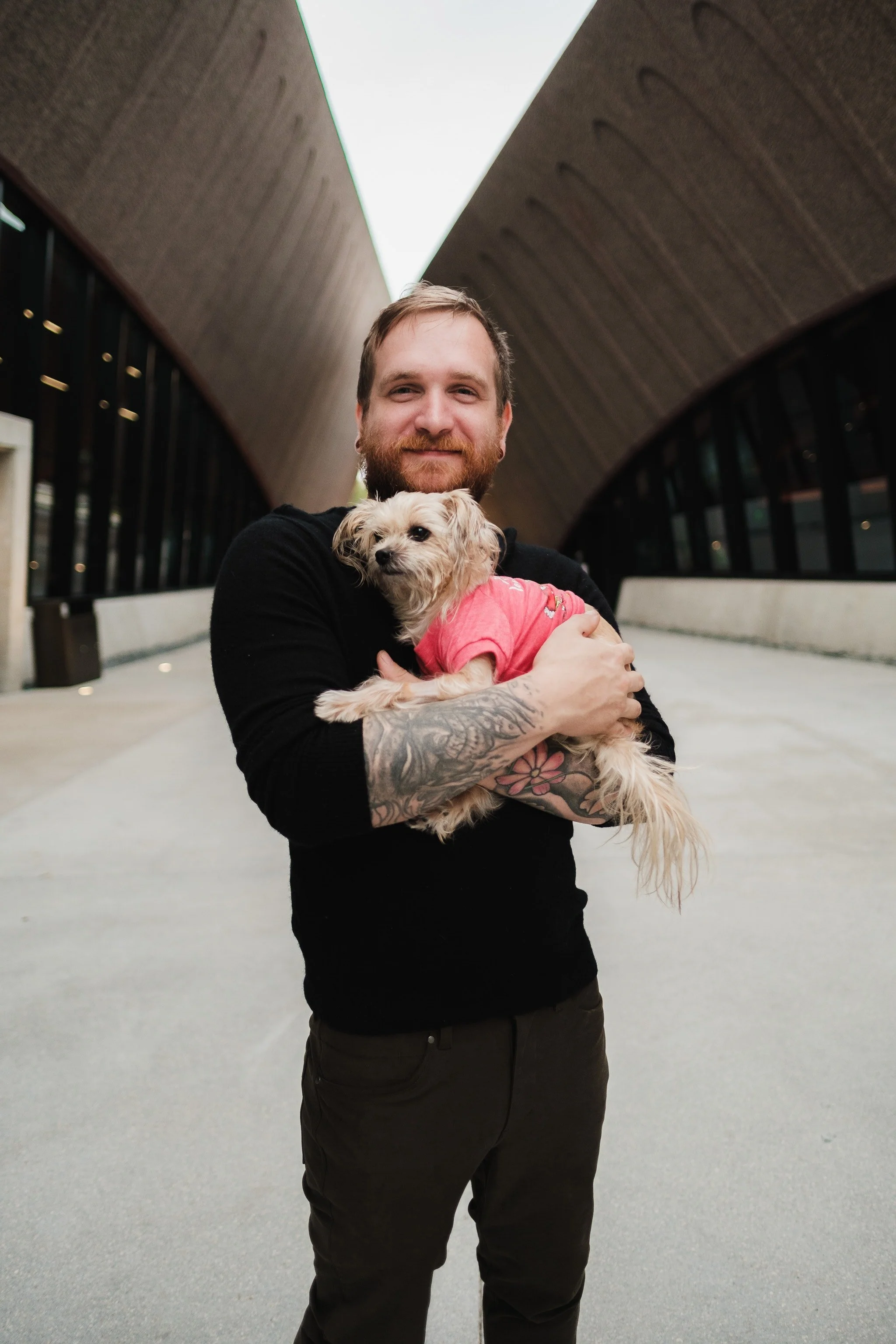 man with tattoos holding puppy in airport