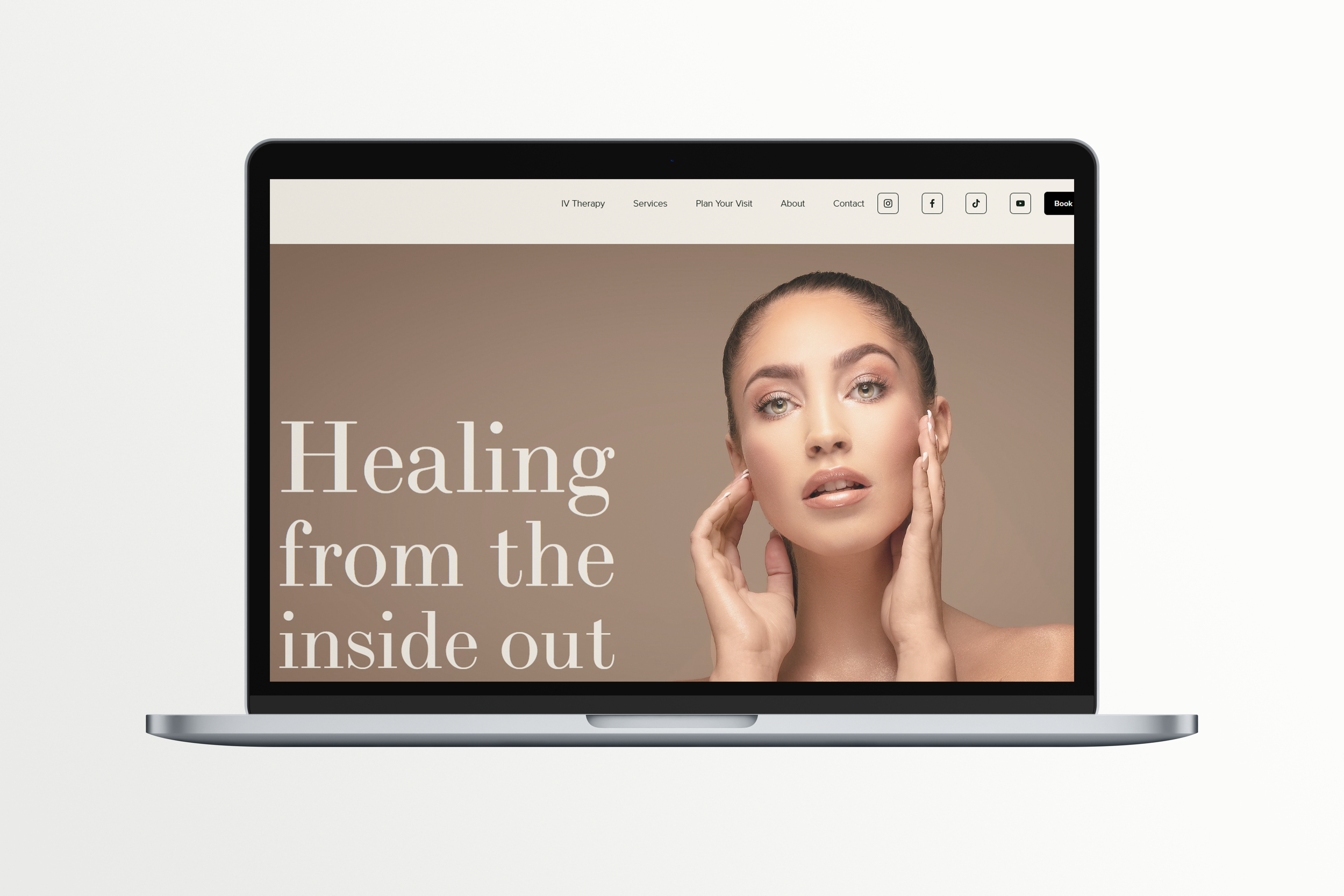 Laptop displaying a webpage with a model touching her face and text reading "Healing from the inside out." Navigation links are at the top.