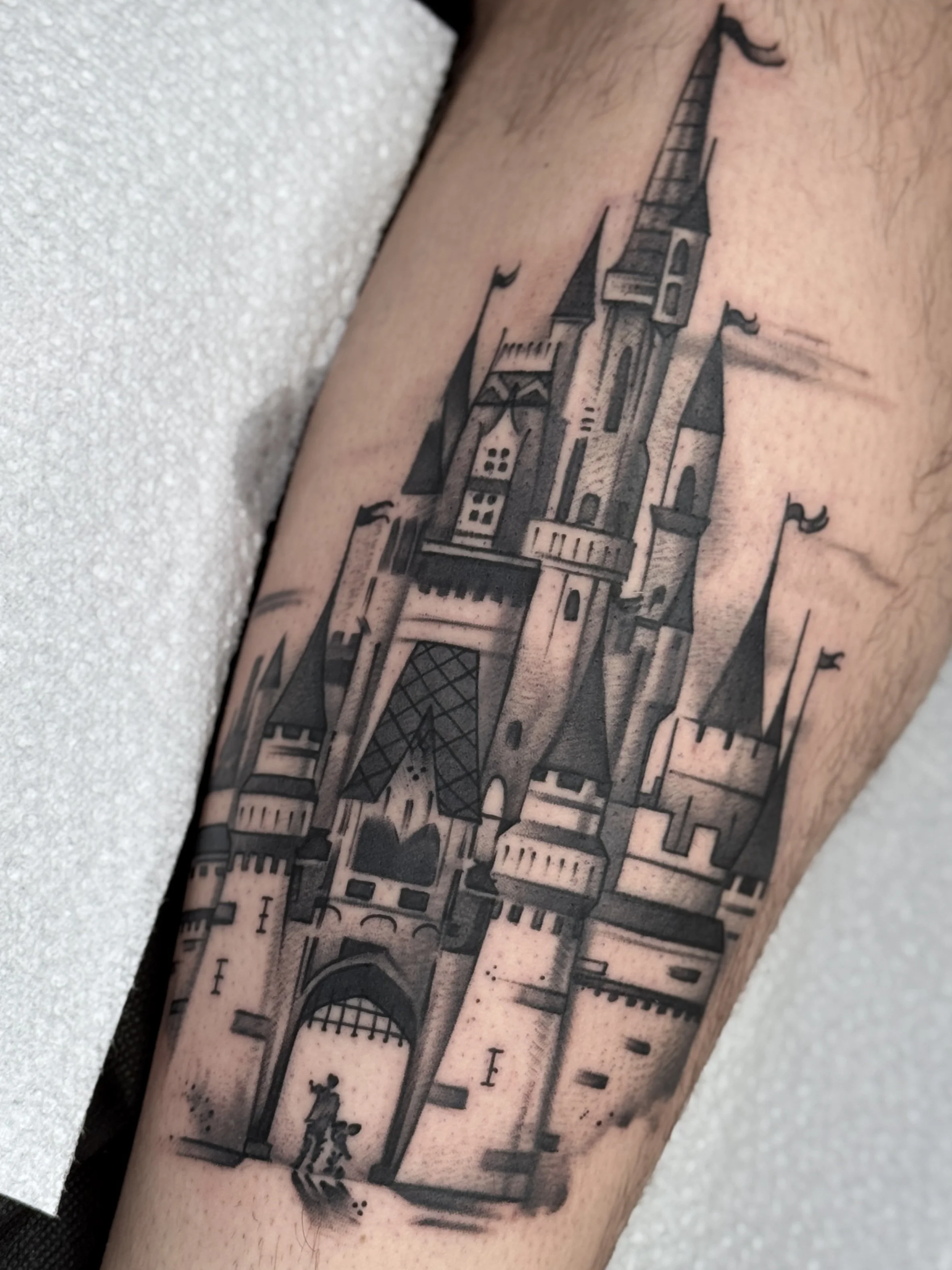 Tattoo of a detailed castle with tall towers and flags.