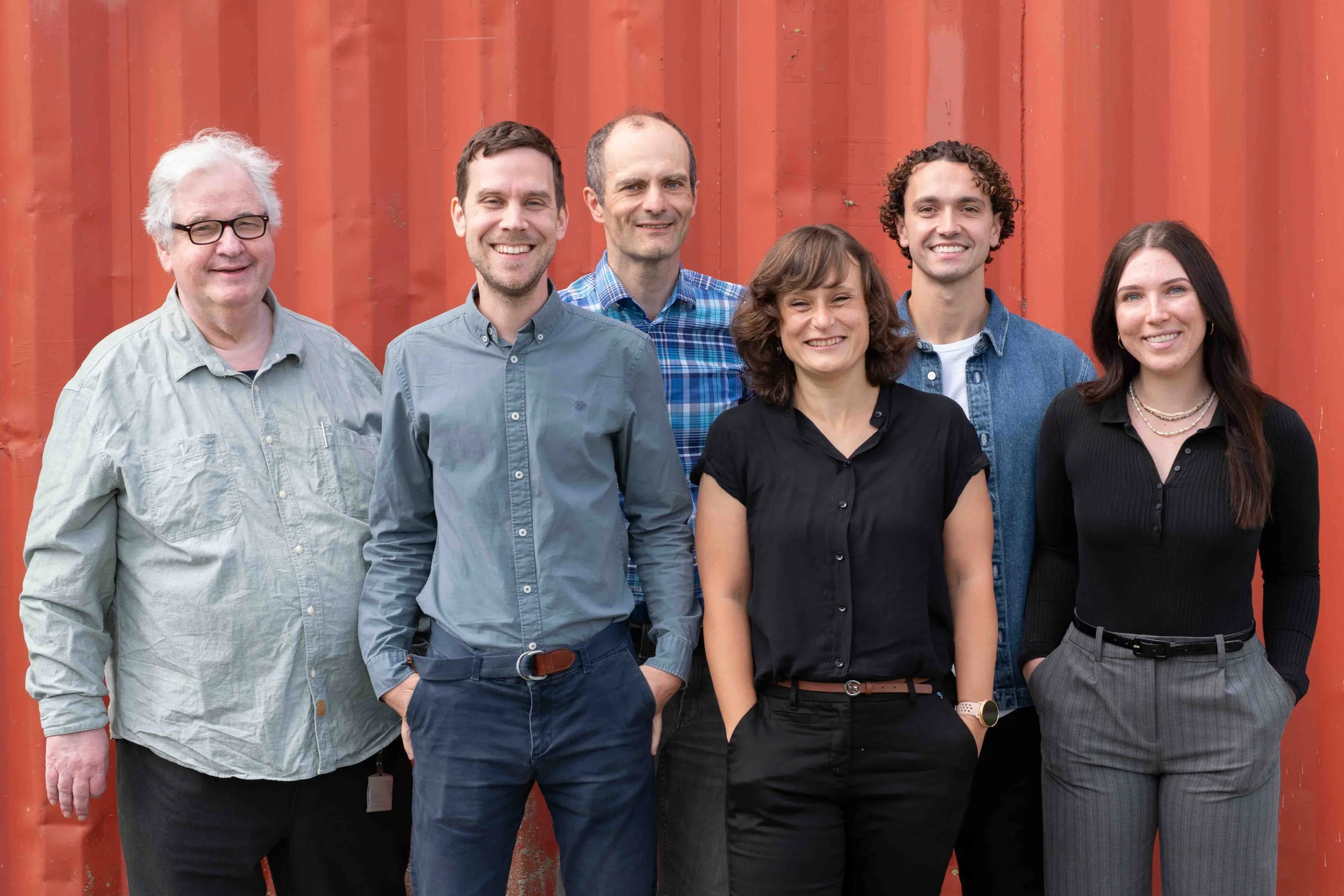 Eddytec staff team photo against a red industrial background at Amsterdam Science Park