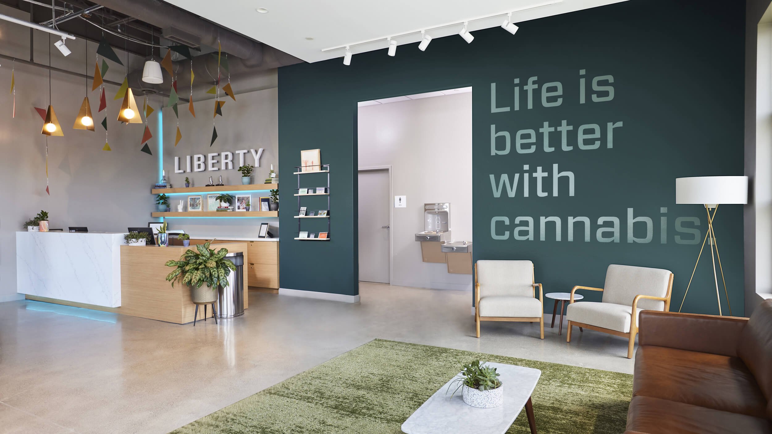 Dispensary entrance desk next to dark green wall saying "life is better with cannabis"