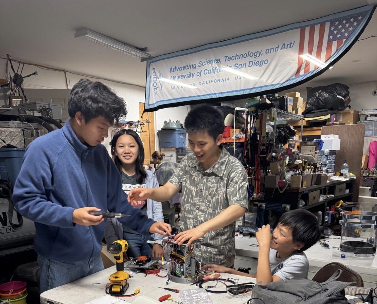 Team members collaborate on electrical assembly.