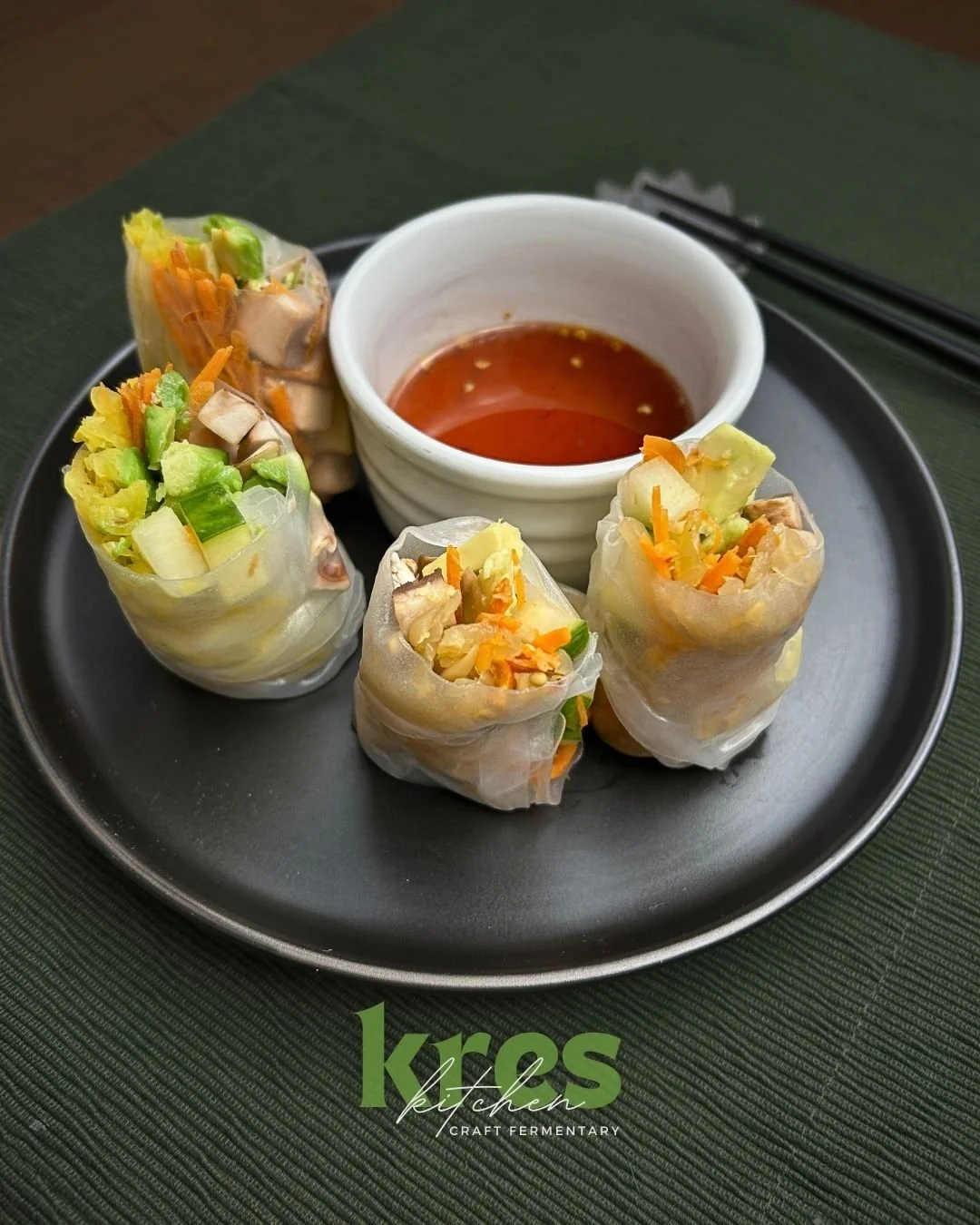 Four spring roles made with golden sauerkraut, fresh diced cucumber, shiitake mushroom and shredded carrots. Small ramekin of Kres Swicy Sauce for dipping. Chop sticks to the side of the  plate.