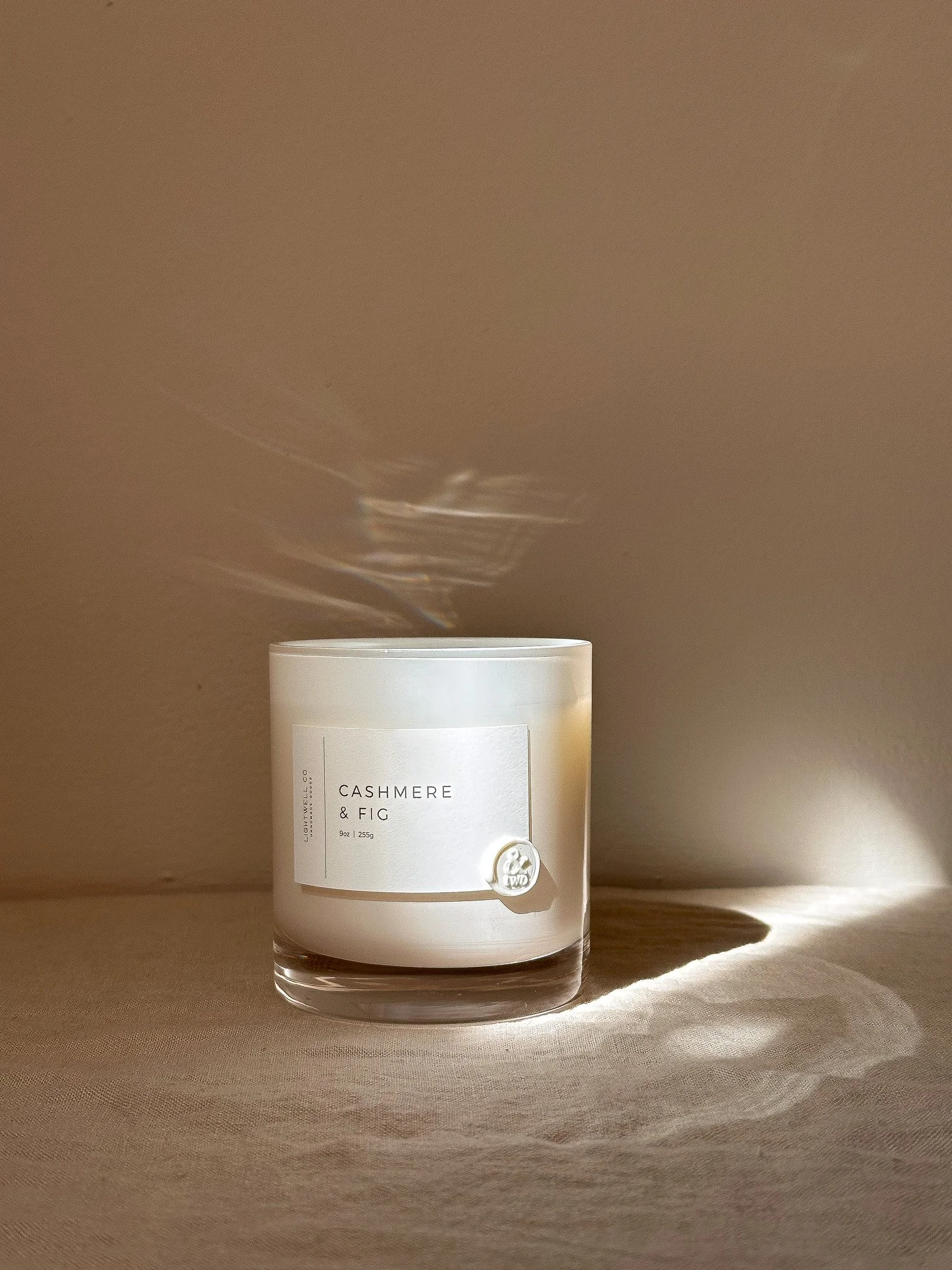 Candle in white glass tumbler on table.