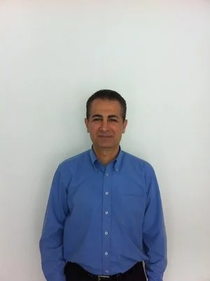 Man in blue shirt standing against white background