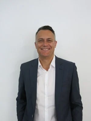 Man in a suit smiling against a plain background