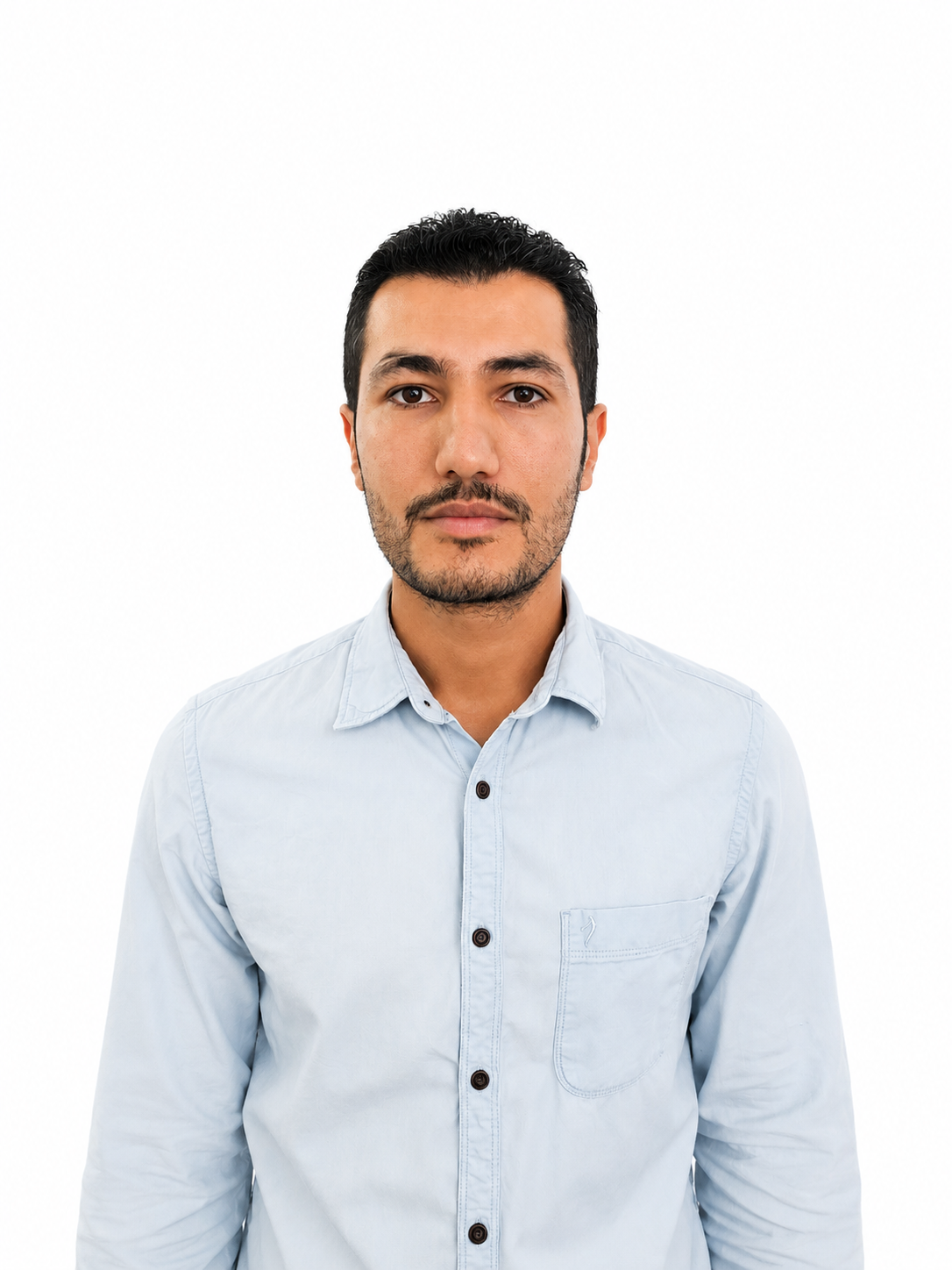 Man in light blue button-up shirt with a neutral expression standing against a plain background.