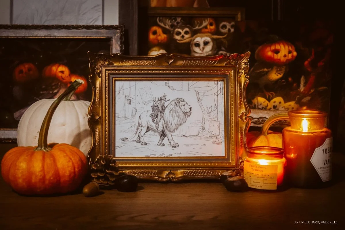 A Halloween-themed display with pumpkins, candles, and framed artwork of a lion with a rider. There are Halloween decorations with carved pumpkins and owl masks in the background.