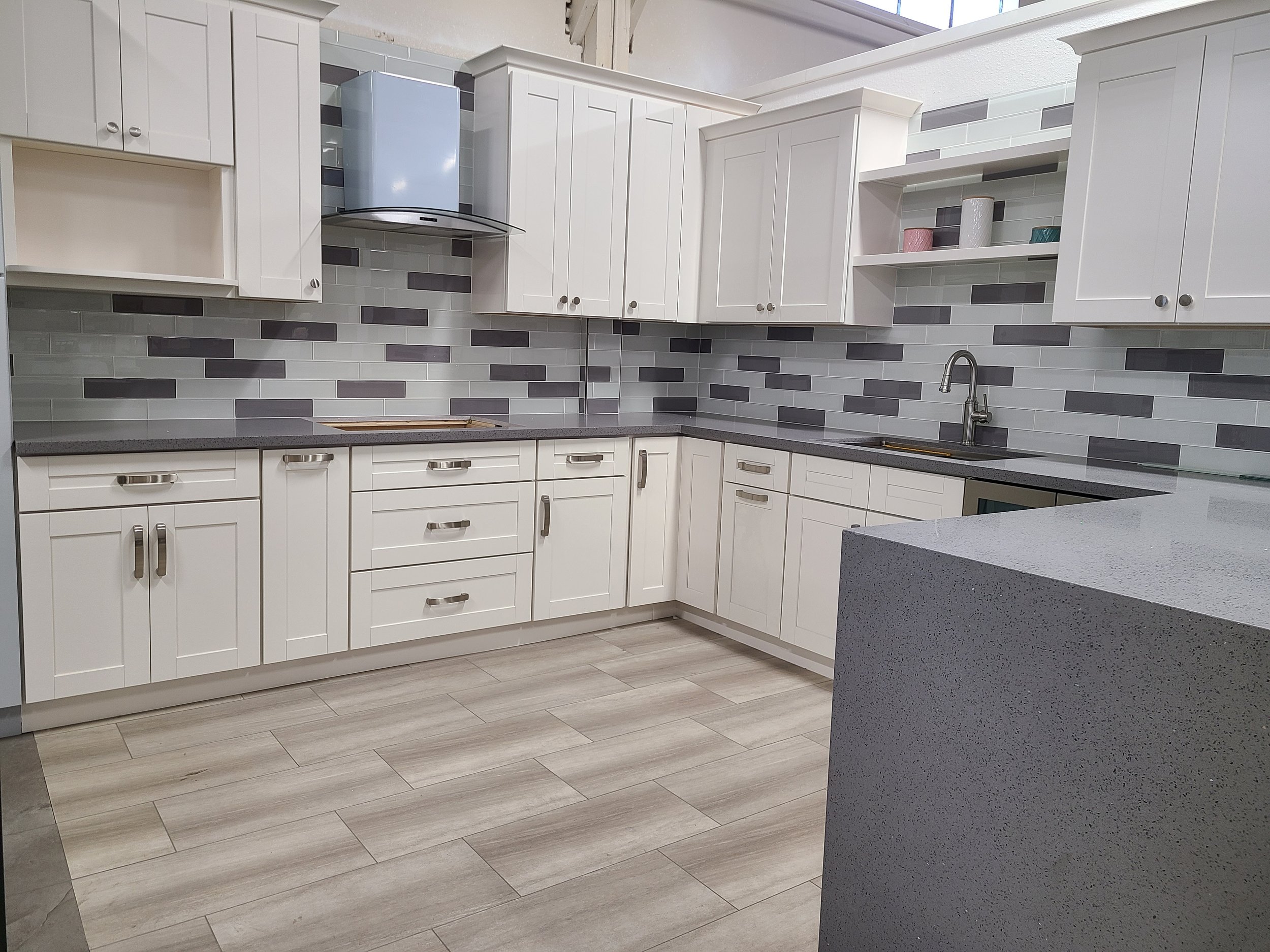 Modern kitchen with white cabinets, gray countertops, and tiled backsplash.