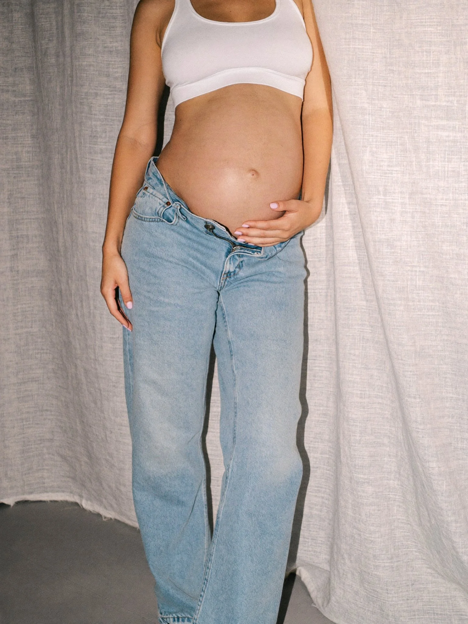 Mothers Day - Pregnant woman holding belly in casual denim and white top - TVS.jpg