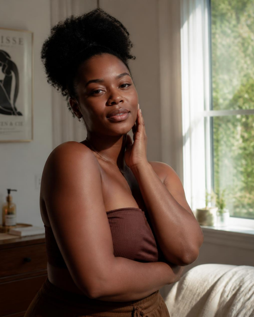 Black woman staring out holding herself with self love