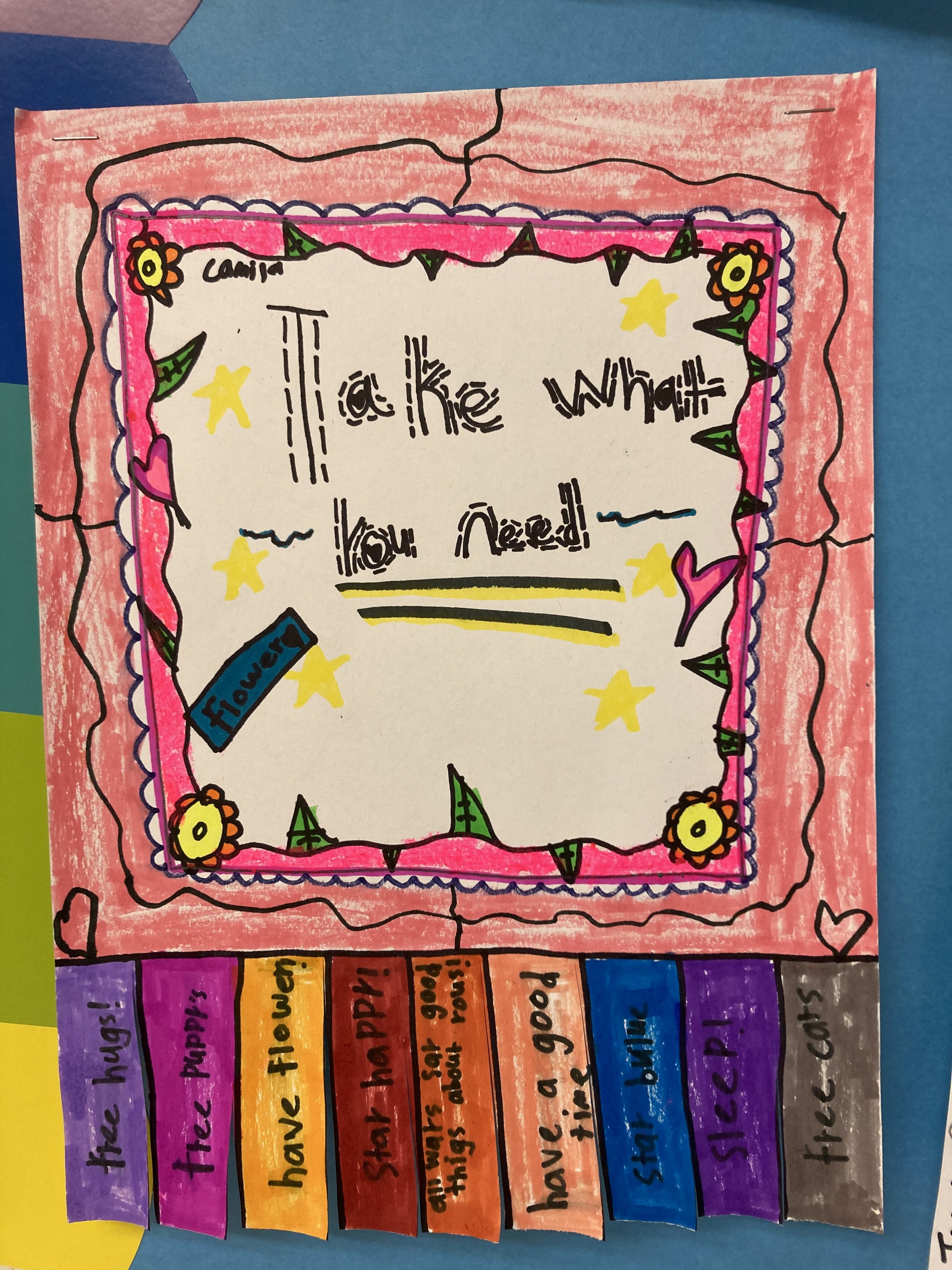 Colorful poster with a message that says, 'Take what you need!' surrounded by decorative stars, flowers, hearts, and banners. The banners at the bottom contain additional messages: 'free hugs!', 'free puzzles!', 'have flowers', 'Share happiness', 'al
