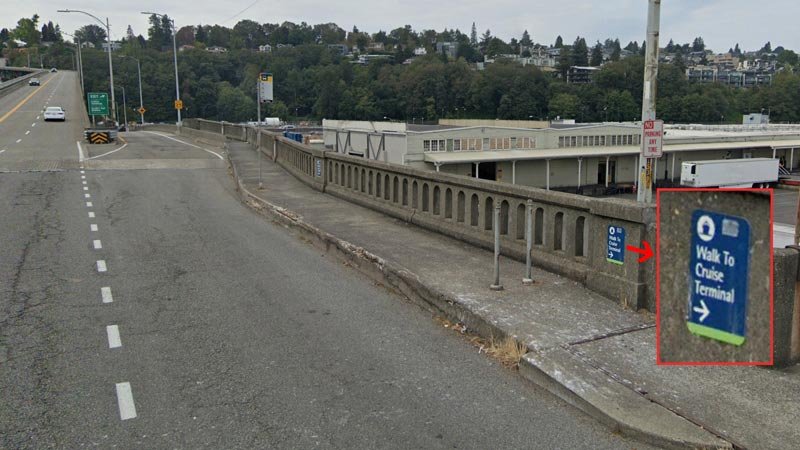  The public transit stop for Seattle’s Pier 91 is on an elevated bridge, with narrow sidewalks and access stairs down to the pier. Signs point the direction to walk to the cruise terminal  Image:   Google Street View  