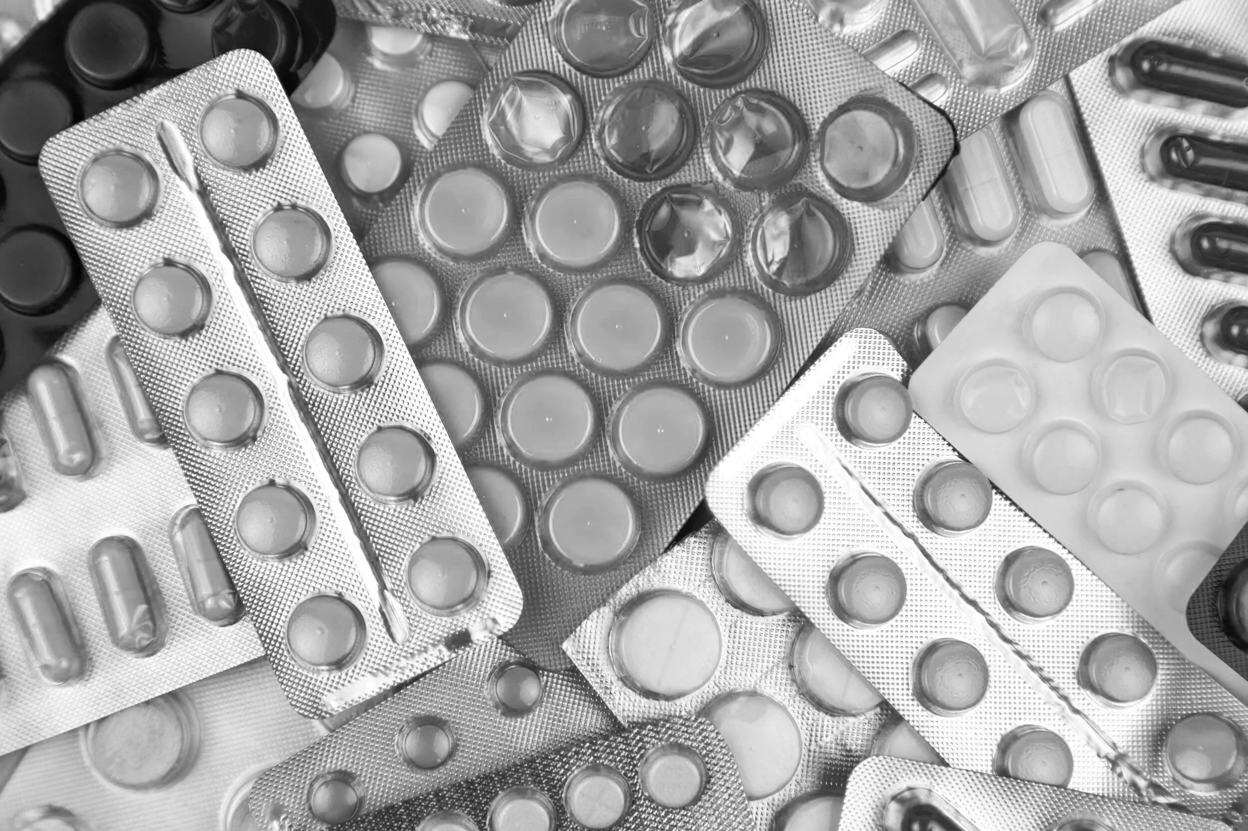 Multiple blister packs of pills and capsules stacked together.