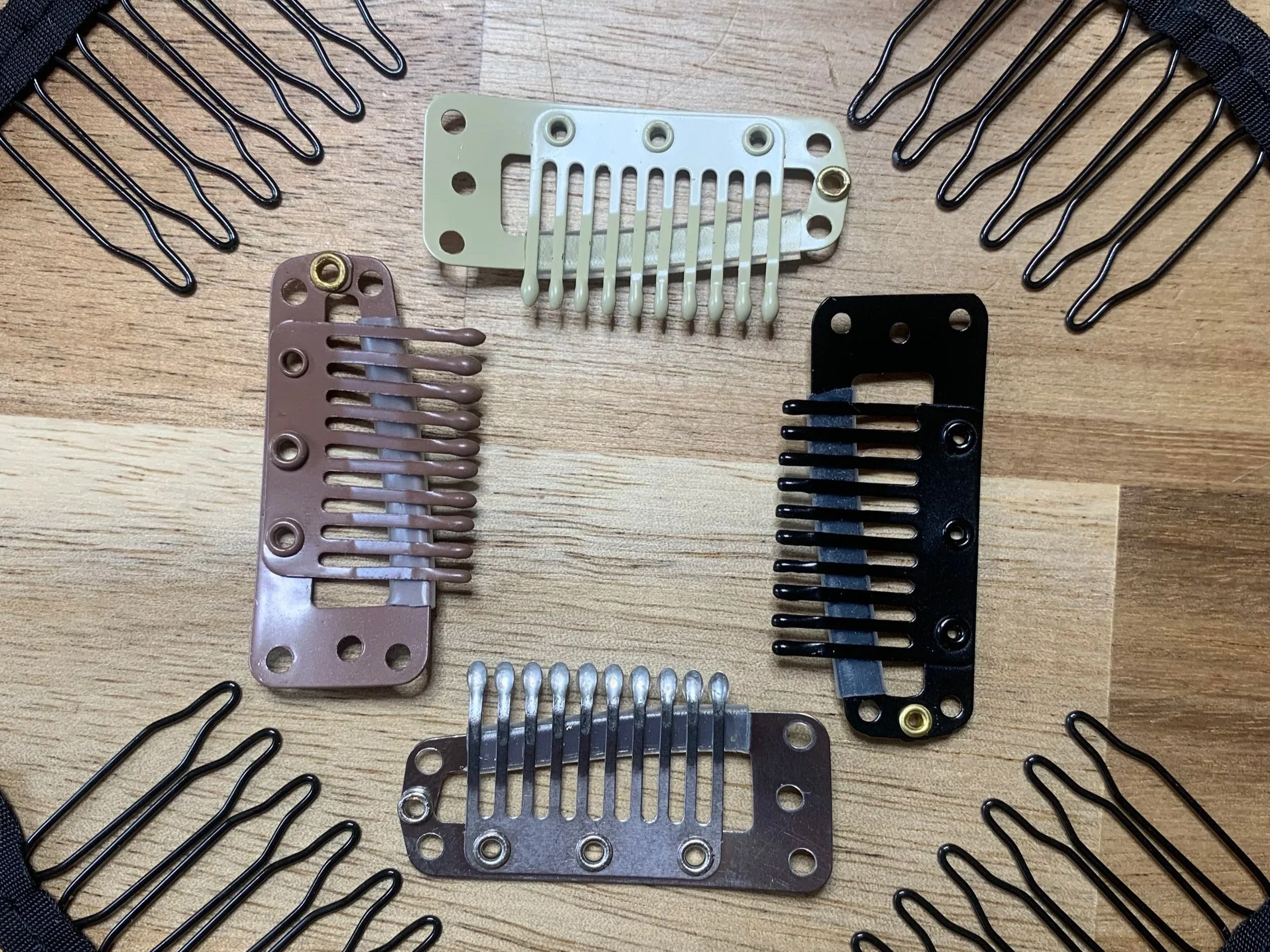 A collection of guitar pickup covers and black pickup mounting brackets arranged on a wooden surface.