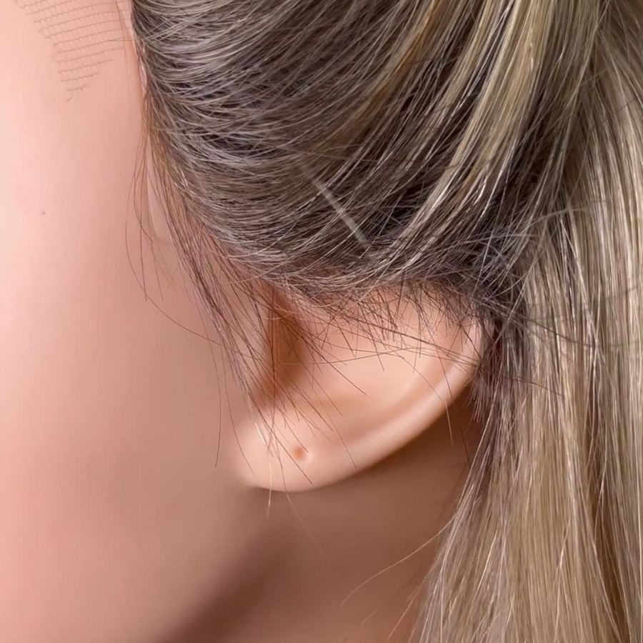 Close-up of a person's ear with light brown hair
