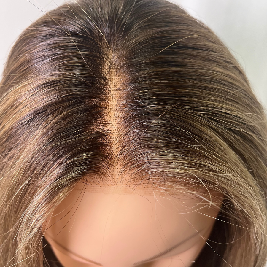 Top view of wig after bang replacement service with longer hair tied in where the bangs once existed.