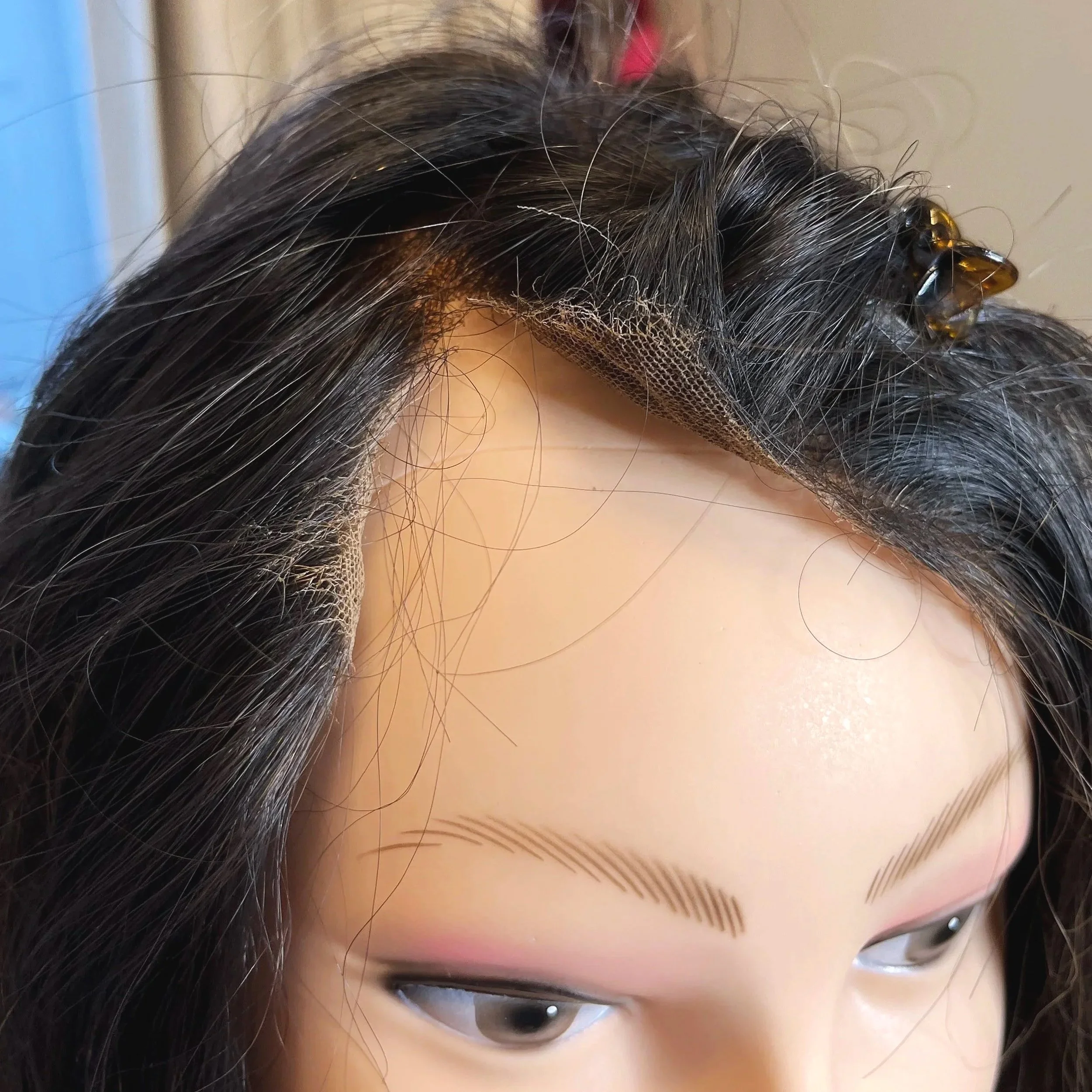 Dark wig on mannequin head and the front of the lace is ripped open