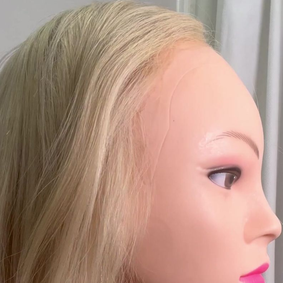 Close-up photo of a mannequin head with blonde hair, realistic facial features, and makeup, seen from the side.