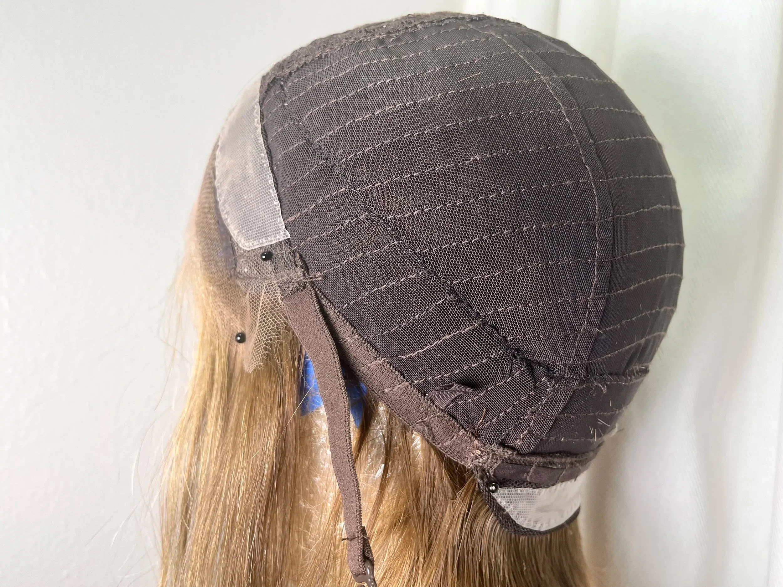 The inside of a wig showing a finished wig cap alteration to reduce excess fabric and create a snug fit.