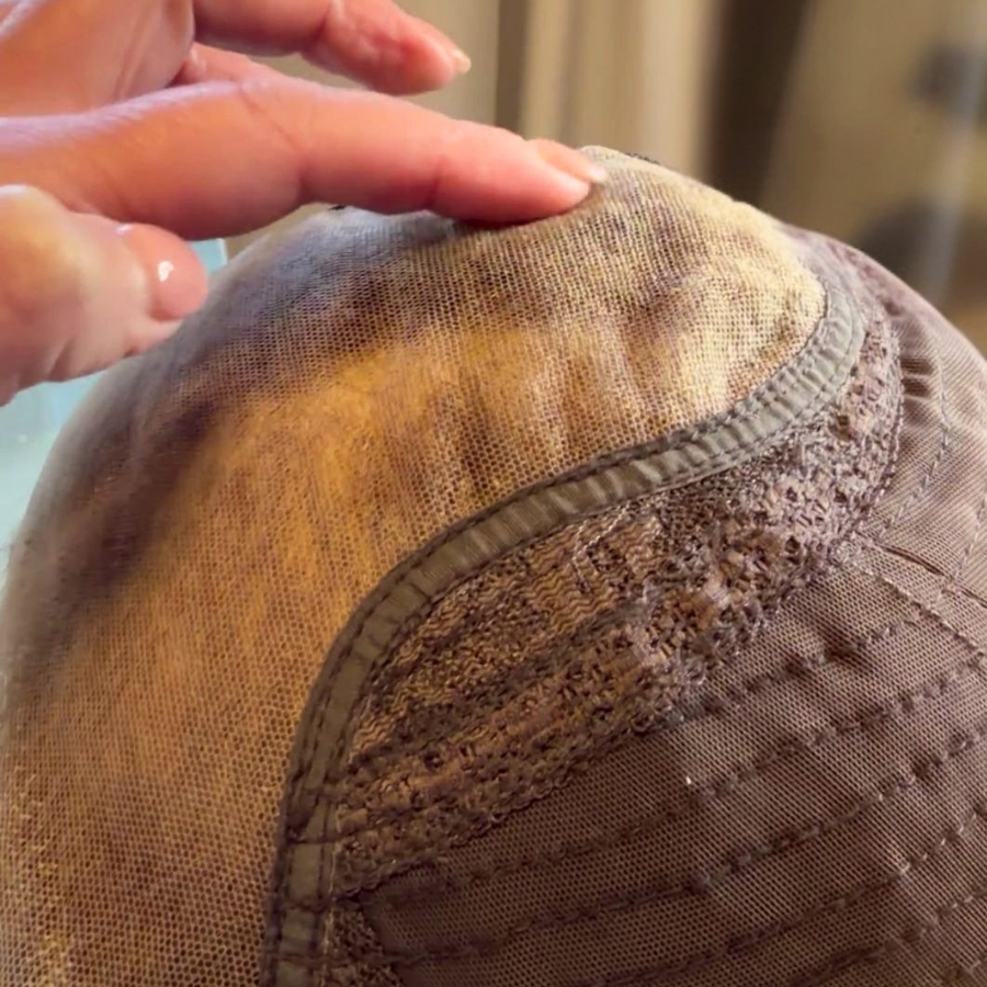 Close-up of a worn-out beige and brown fabric hat with visible fraying and damage.
