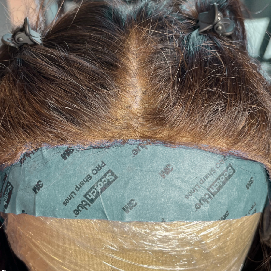 Front close up of dark wig on canvas block with thinning front hairline and part prior to fill in service.