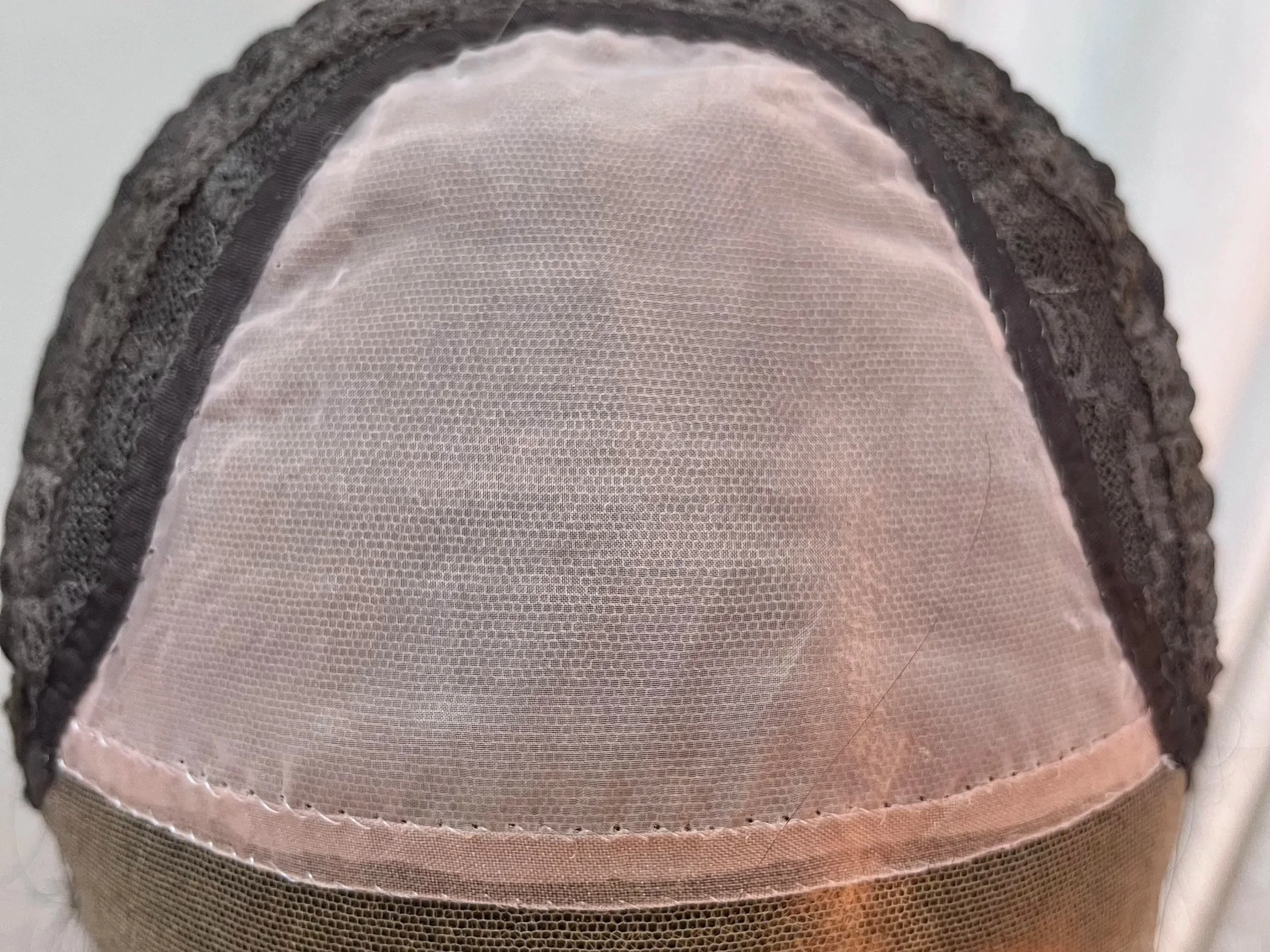 Close-up of a lace front wig cap showing the mesh material and lace detailing.