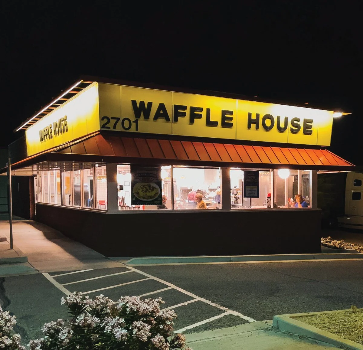 Nighttime photo of a well-lit Waffle House restaurant with large yellow sign, red roof, and visible interior customers, located at 2701.
