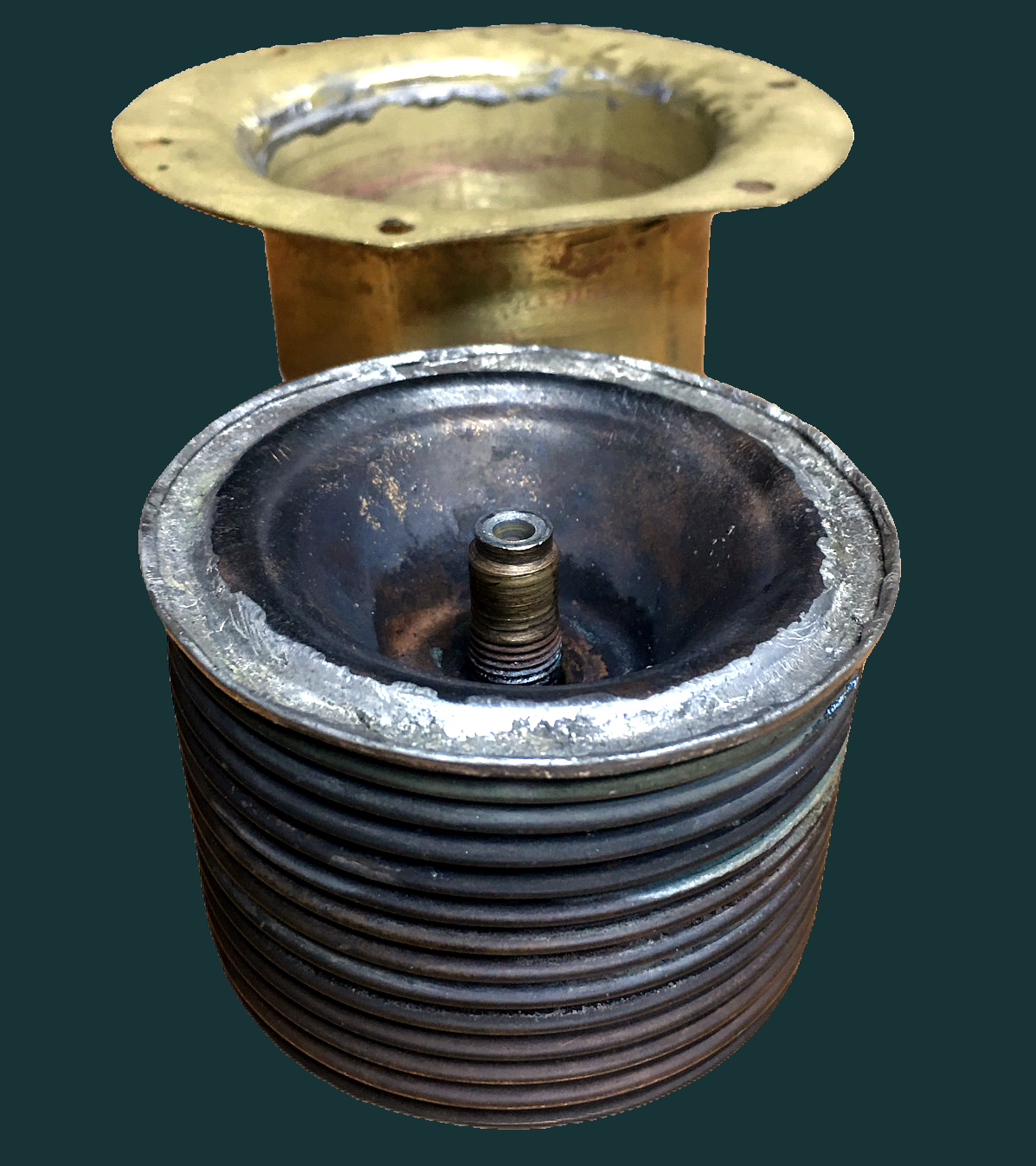 Schwarzer Balgenthermostat neben messingfarbenem Behälter