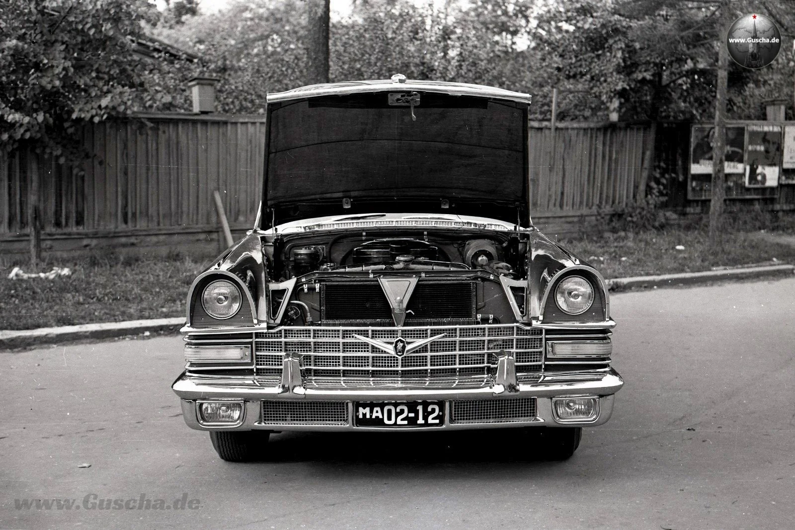 Ein ZIL-111 mit hochgestellter Motorhaube vor einem Gartenzaun