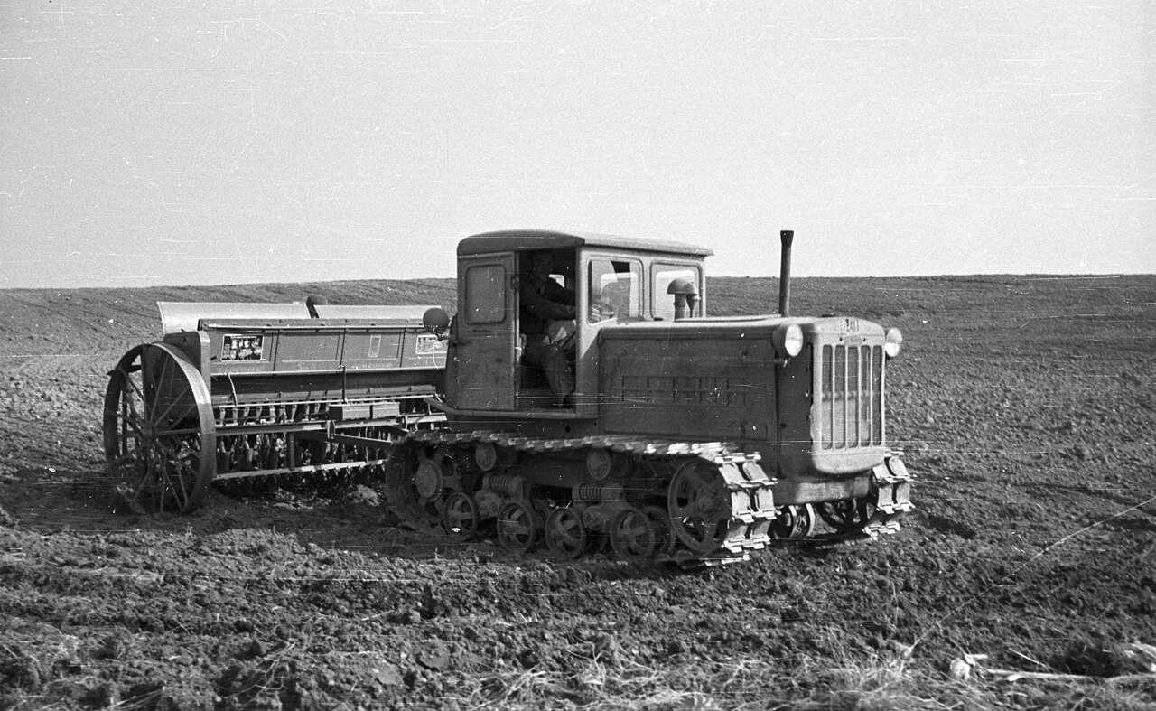 Raupenschlepper mit Anhänger auf einem endlosen Acker