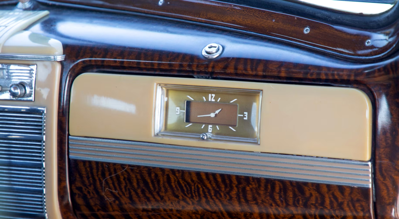Farbaufnahme von rechts vorne zeigt die braungoldene Uhr im Handschuhfach eines Packard