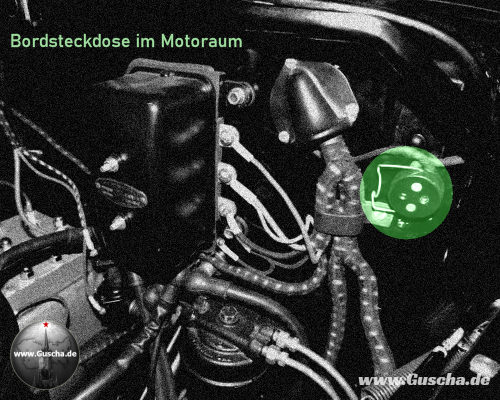 Dunkler Motorraum mit grünlich schimmernd hervorgehobener Steckdose