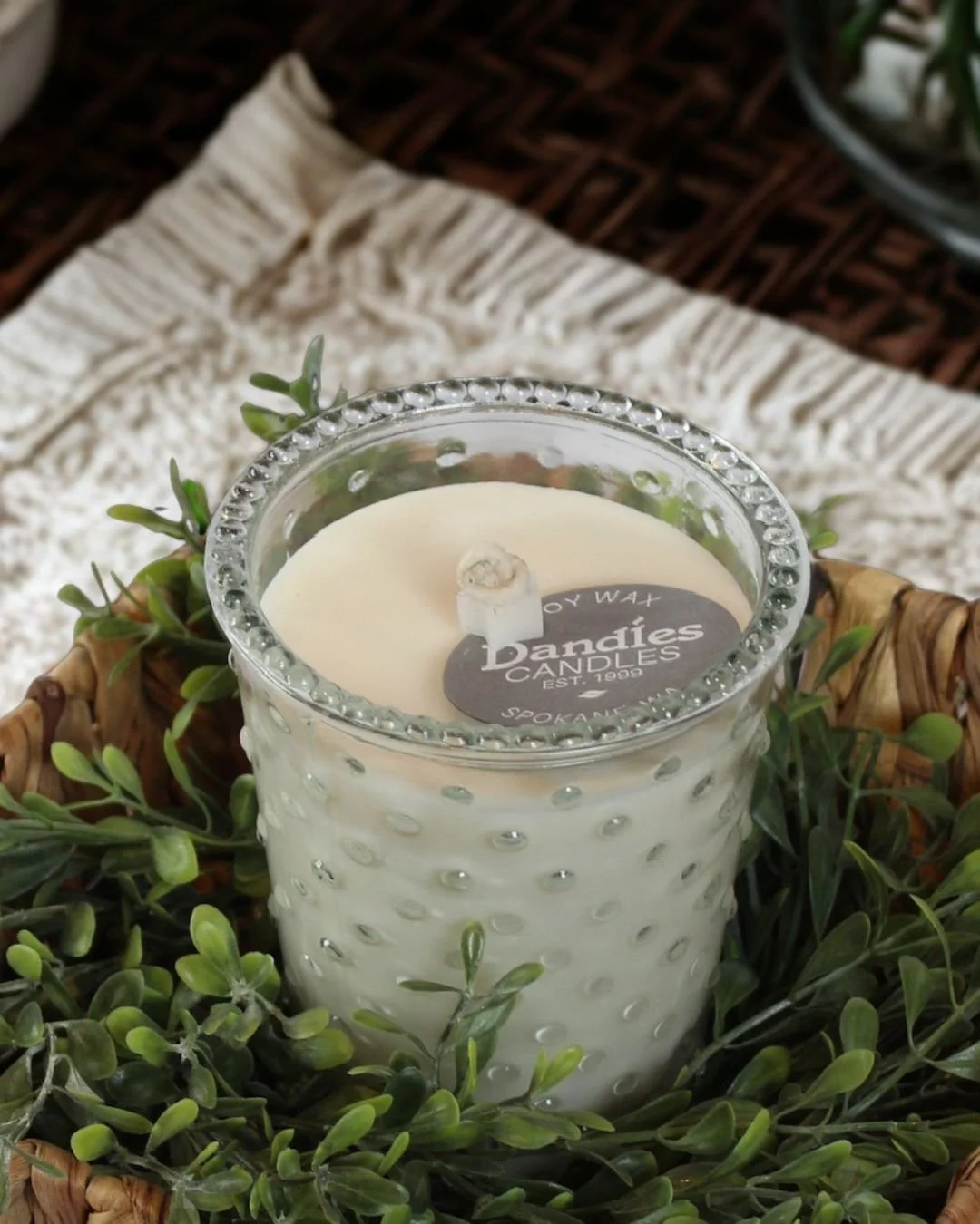 Classic hobnail candle surrounded by greenery