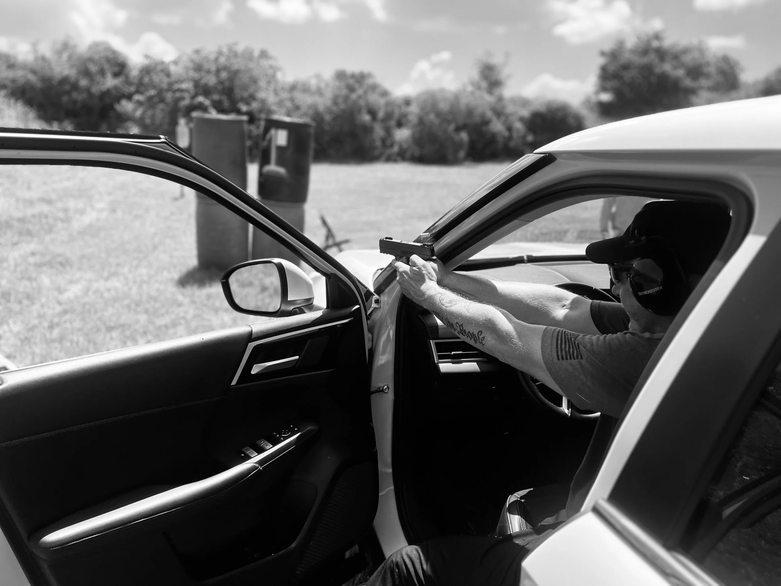 A person aiming a handgun from inside a car. Counter carjacking course. Vehicle tactics. Firearms instruction.