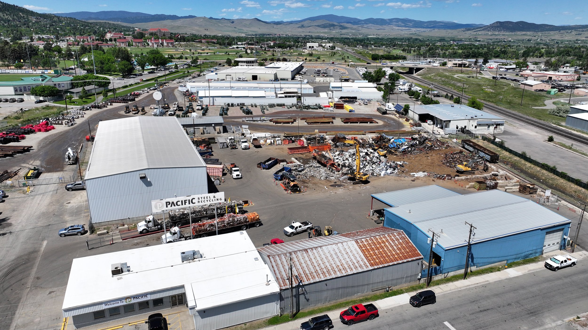Industrial area with warehouses, construction site, and mountains in the background.