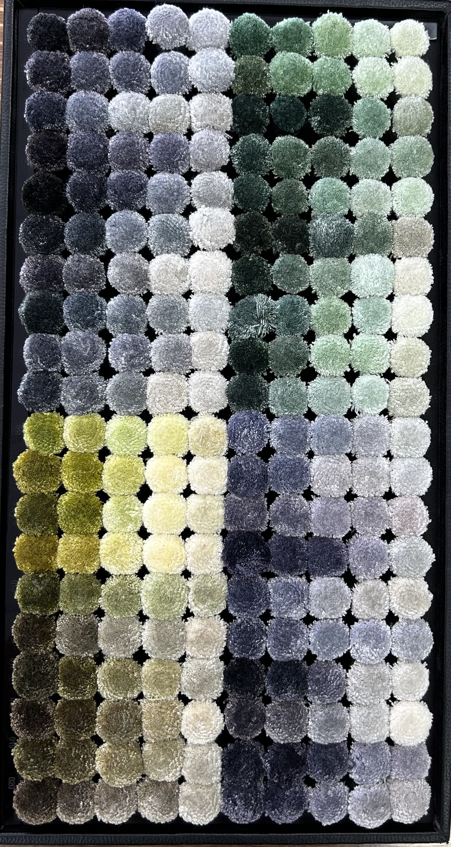 Colorful tufted carpet sample swatches in a grid arrangement, featuring various shades of gray, green, and yellow.