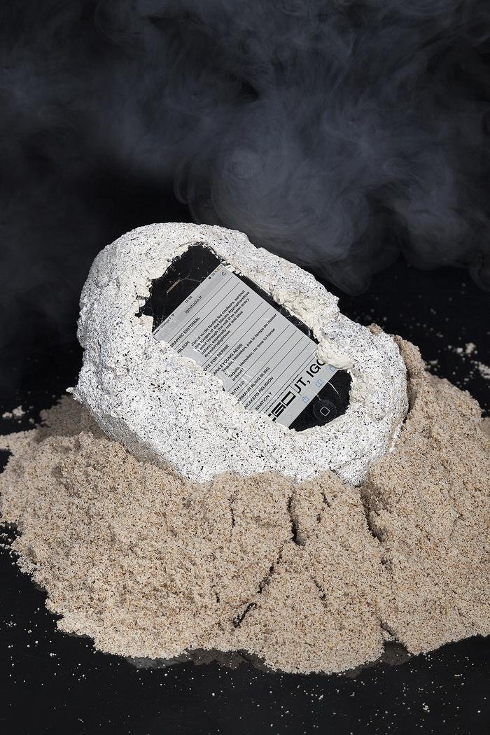 A smartphone placed inside a salt or sand formation with a smoky background.