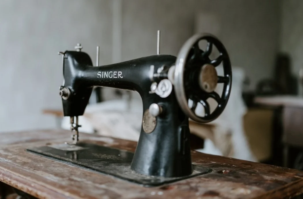 A vintage black Singer sewing machine on a wooden table.