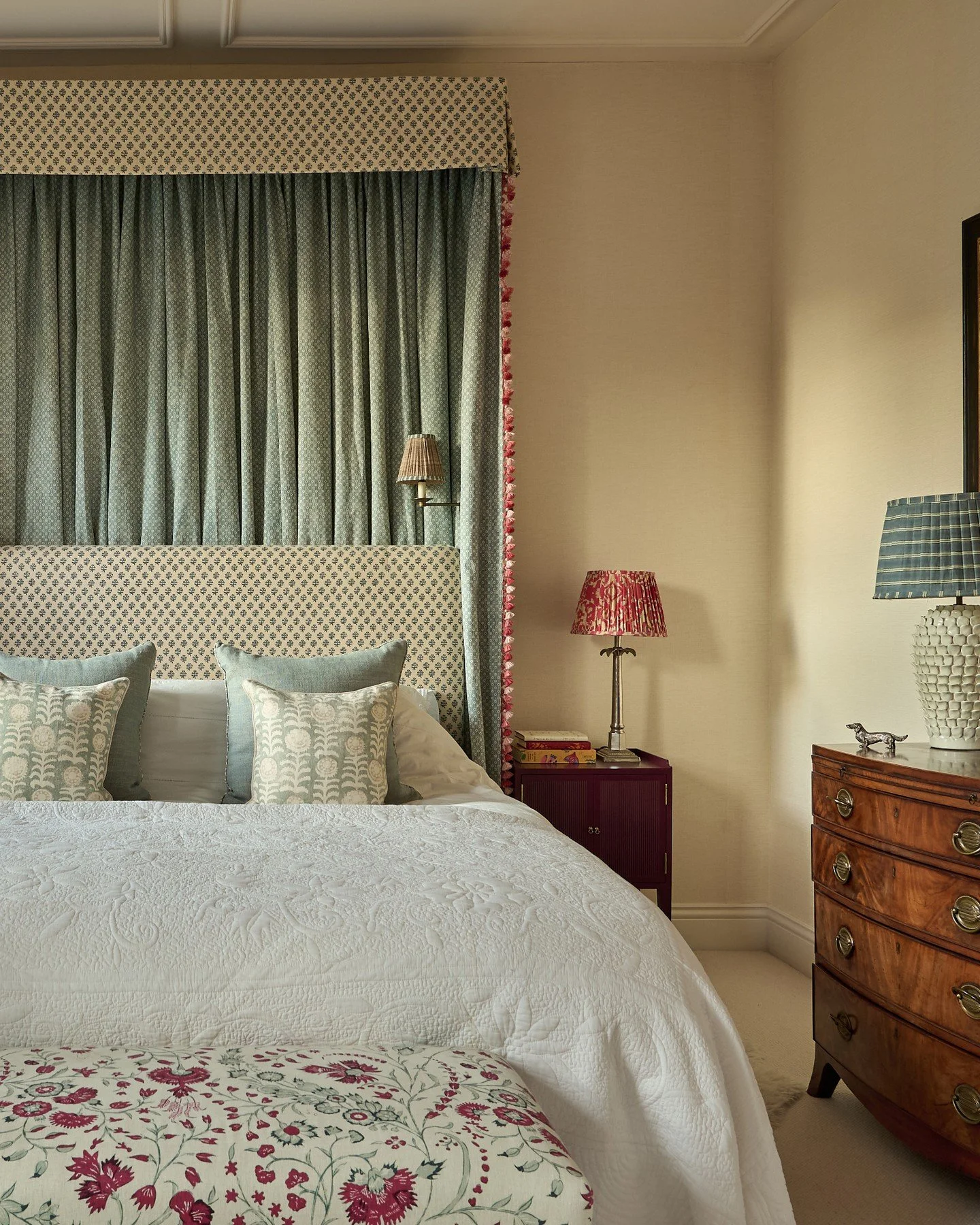 In the master bedroom of our London townhouse project, a half tester behind the headboard helps frame the bed, guide the eye upward, and bring a cosy, cocoon-like quality to the space. We've blended antique finds with our own GWD side tables in this 